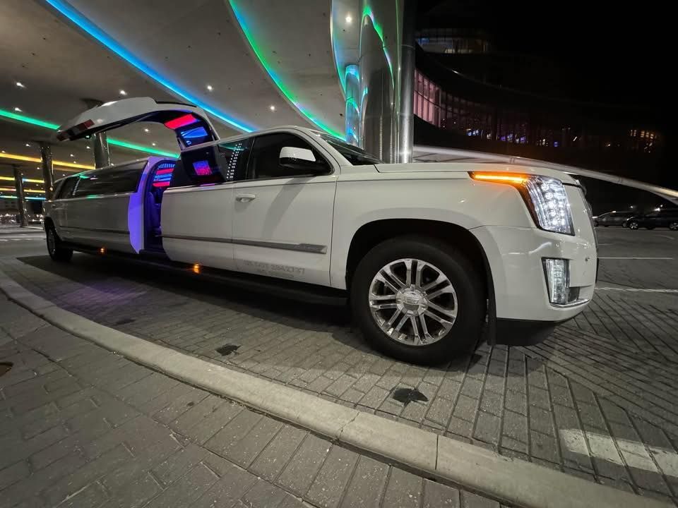 A white limousine with its doors open is parked on the side of the road.