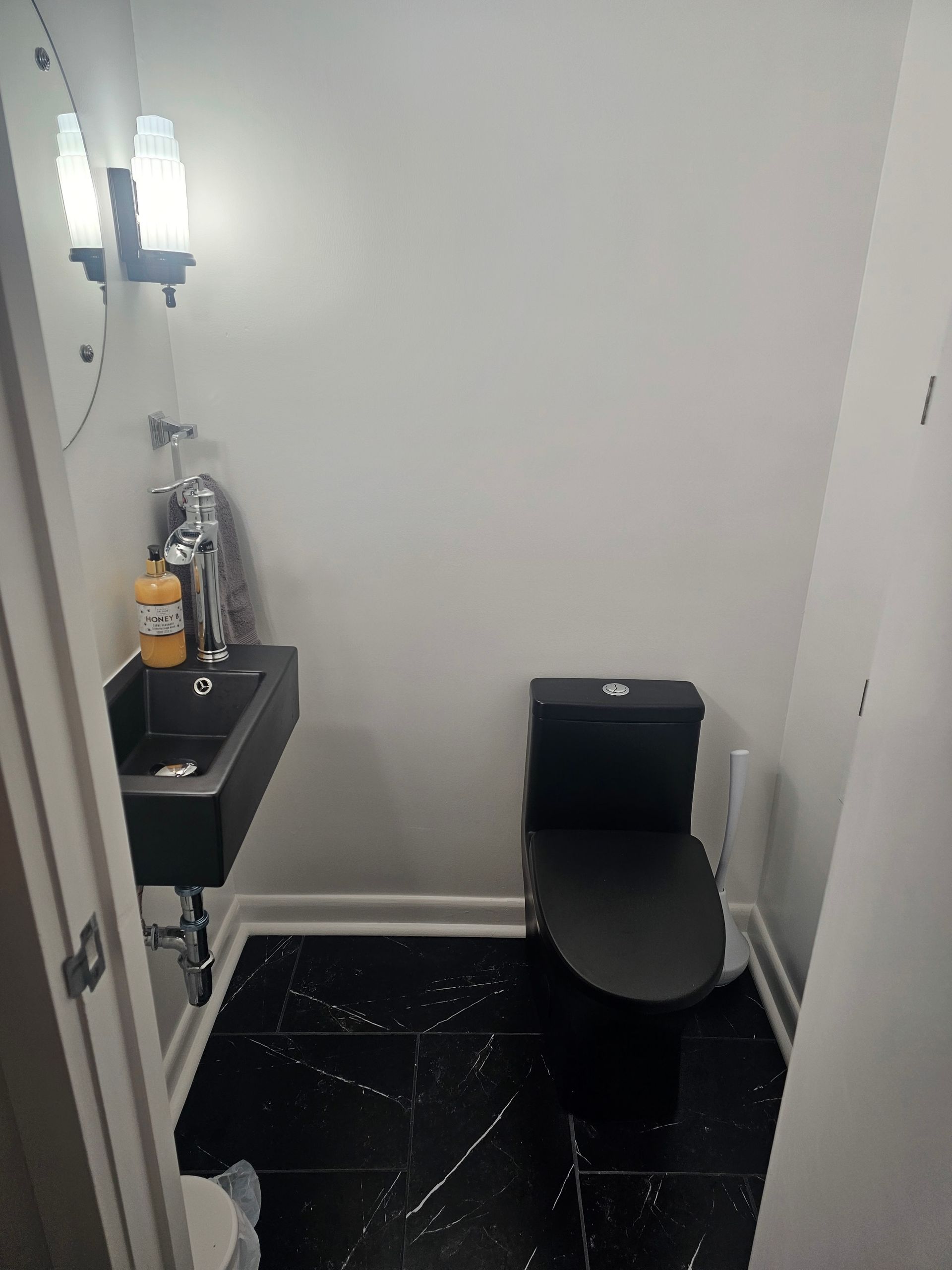 A bathroom with a toilet , sink and mirror.