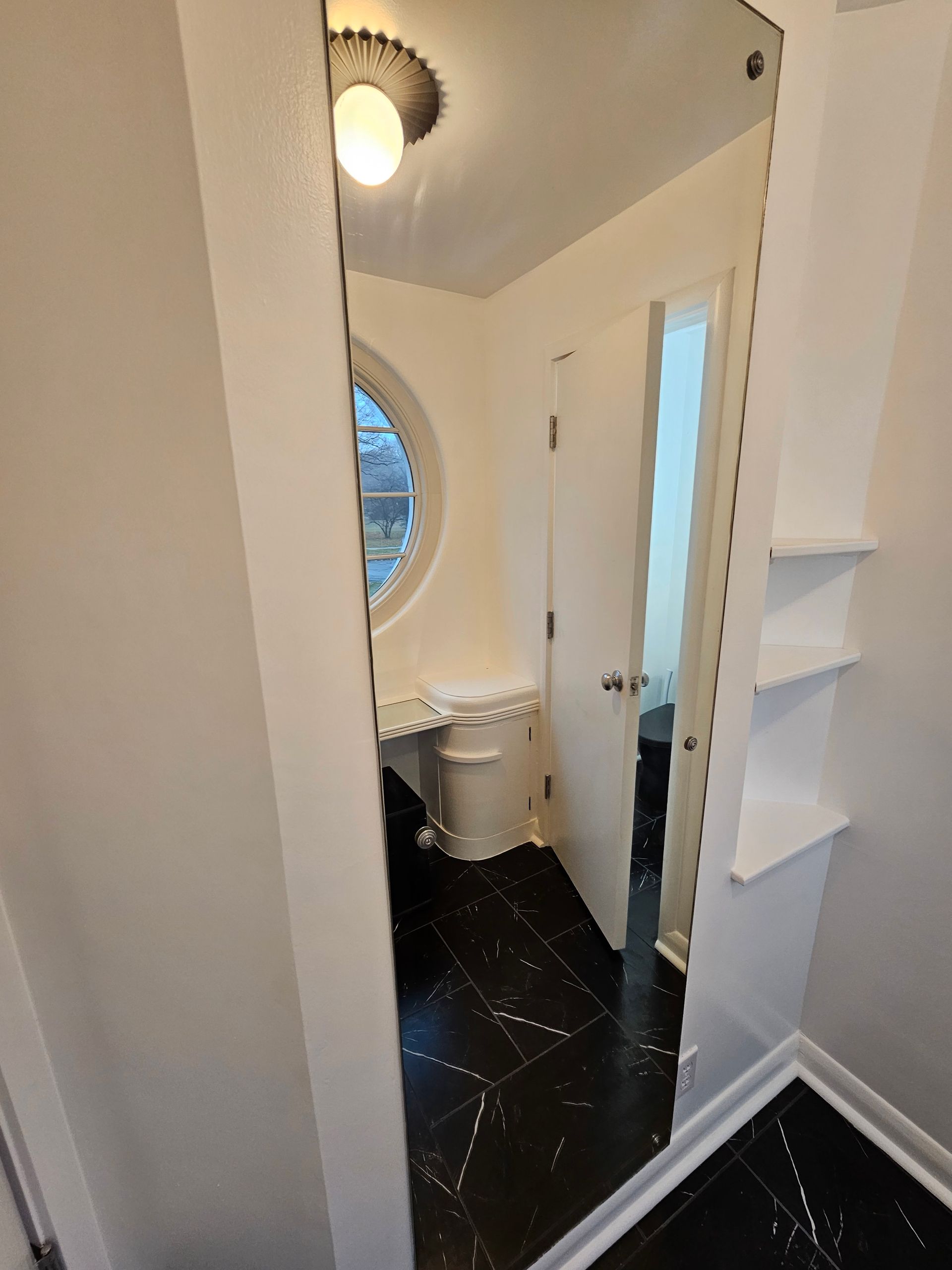 A bathroom with a toilet , sink and mirror.