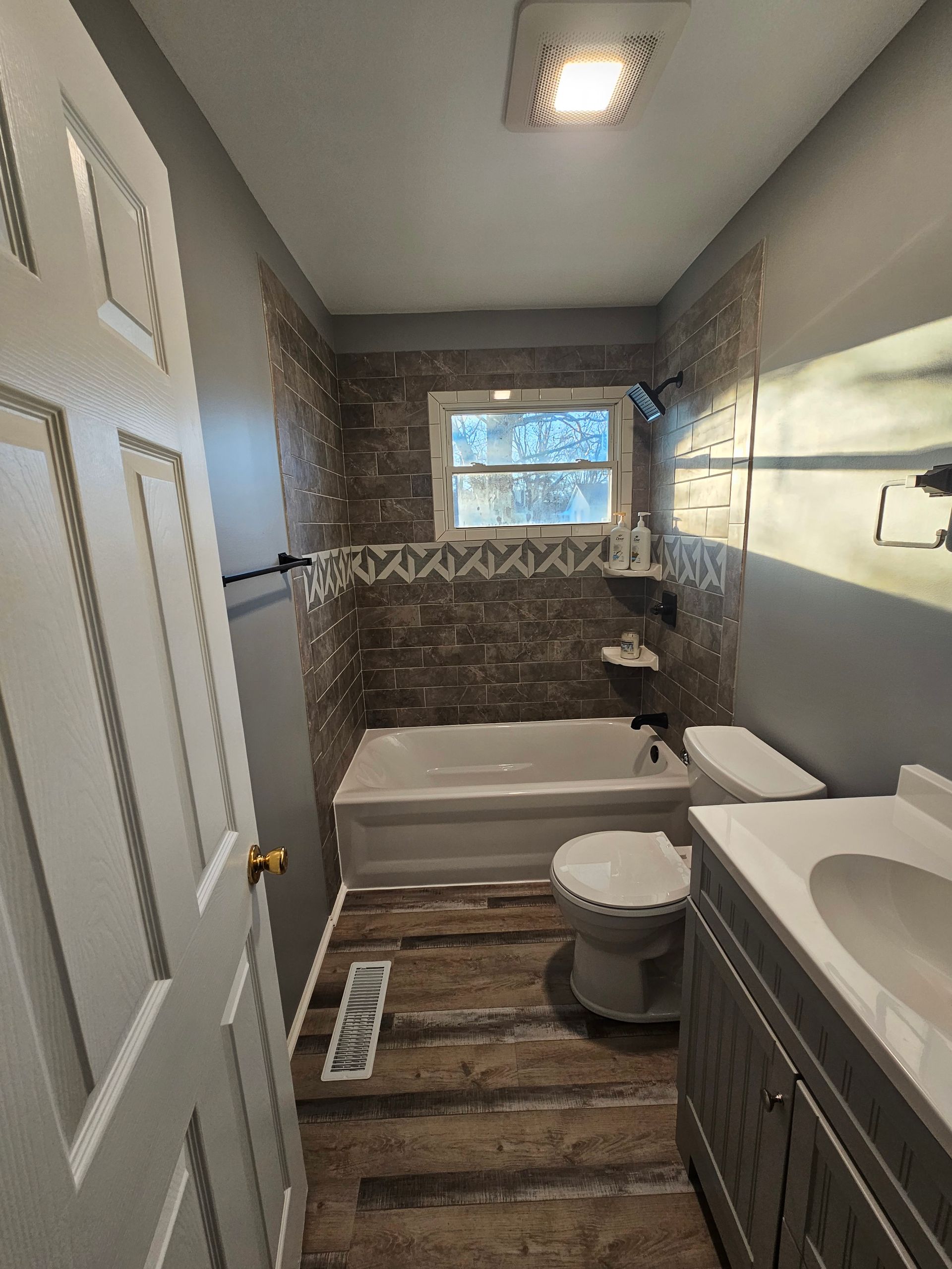 A bathroom with a tub , toilet , sink and mirror.