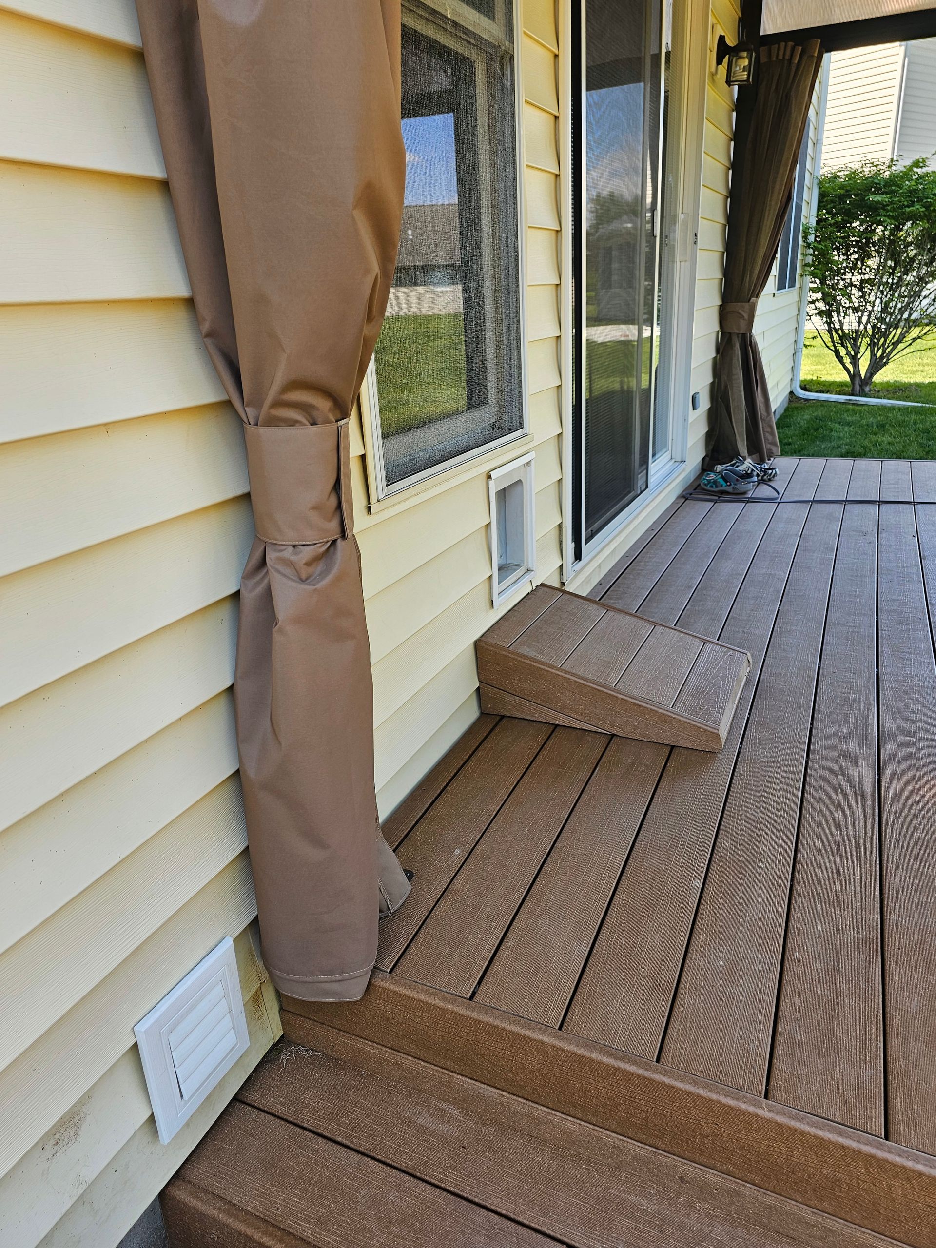 A wooden deck next to a house with a sliding glass door.