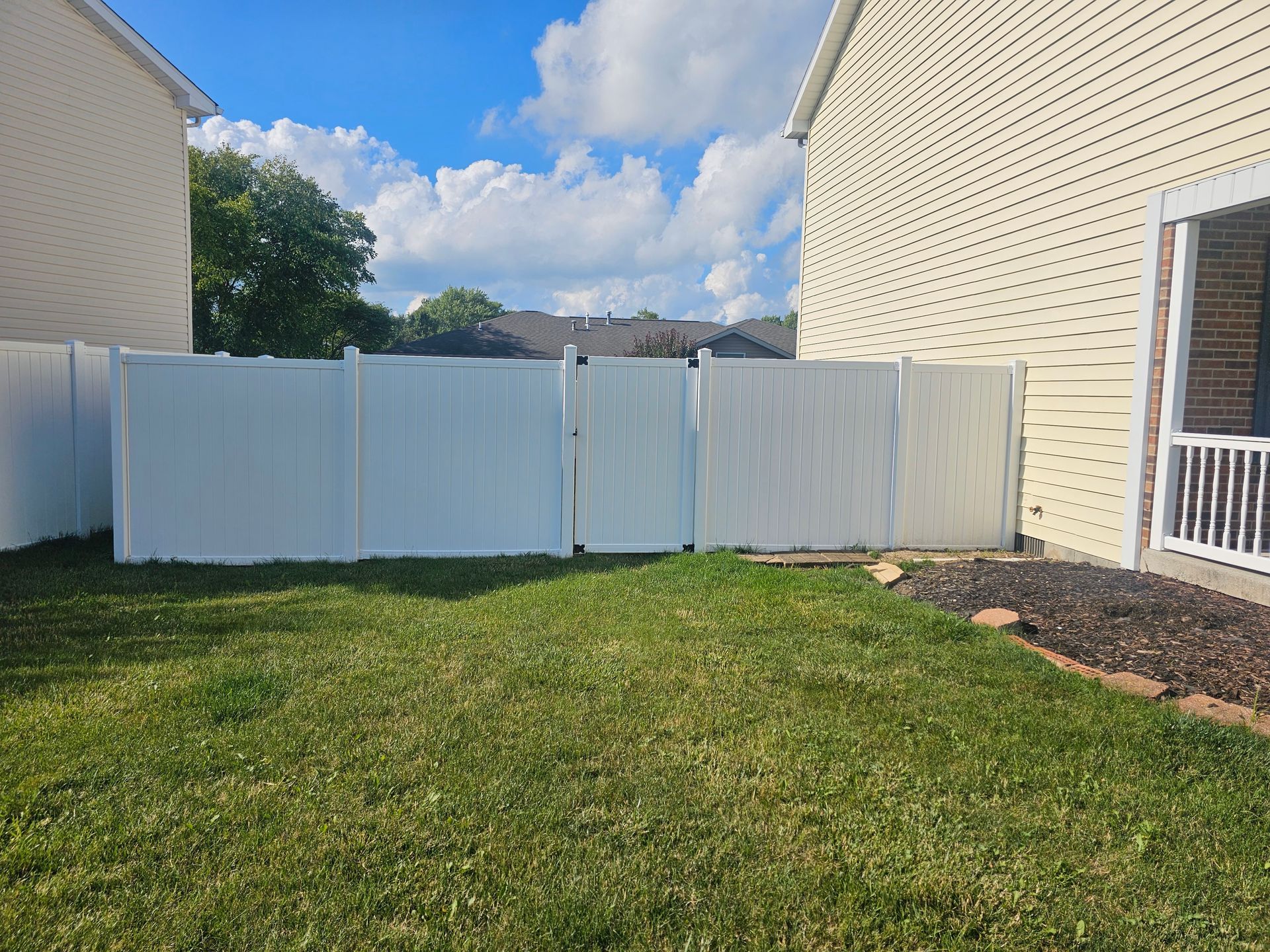 There is a white fence in the backyard of a house.