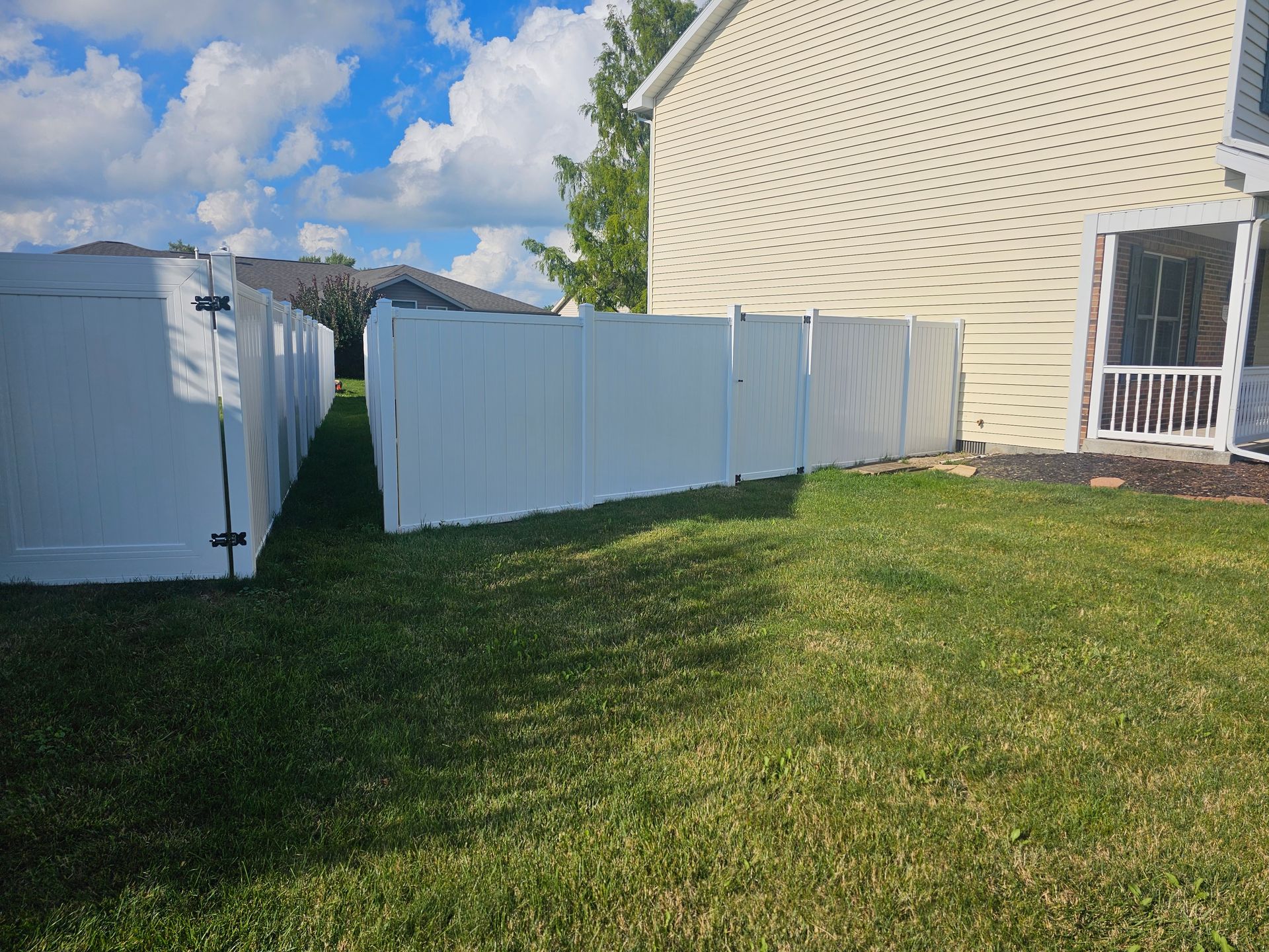 There is a white fence in the backyard of a house.
