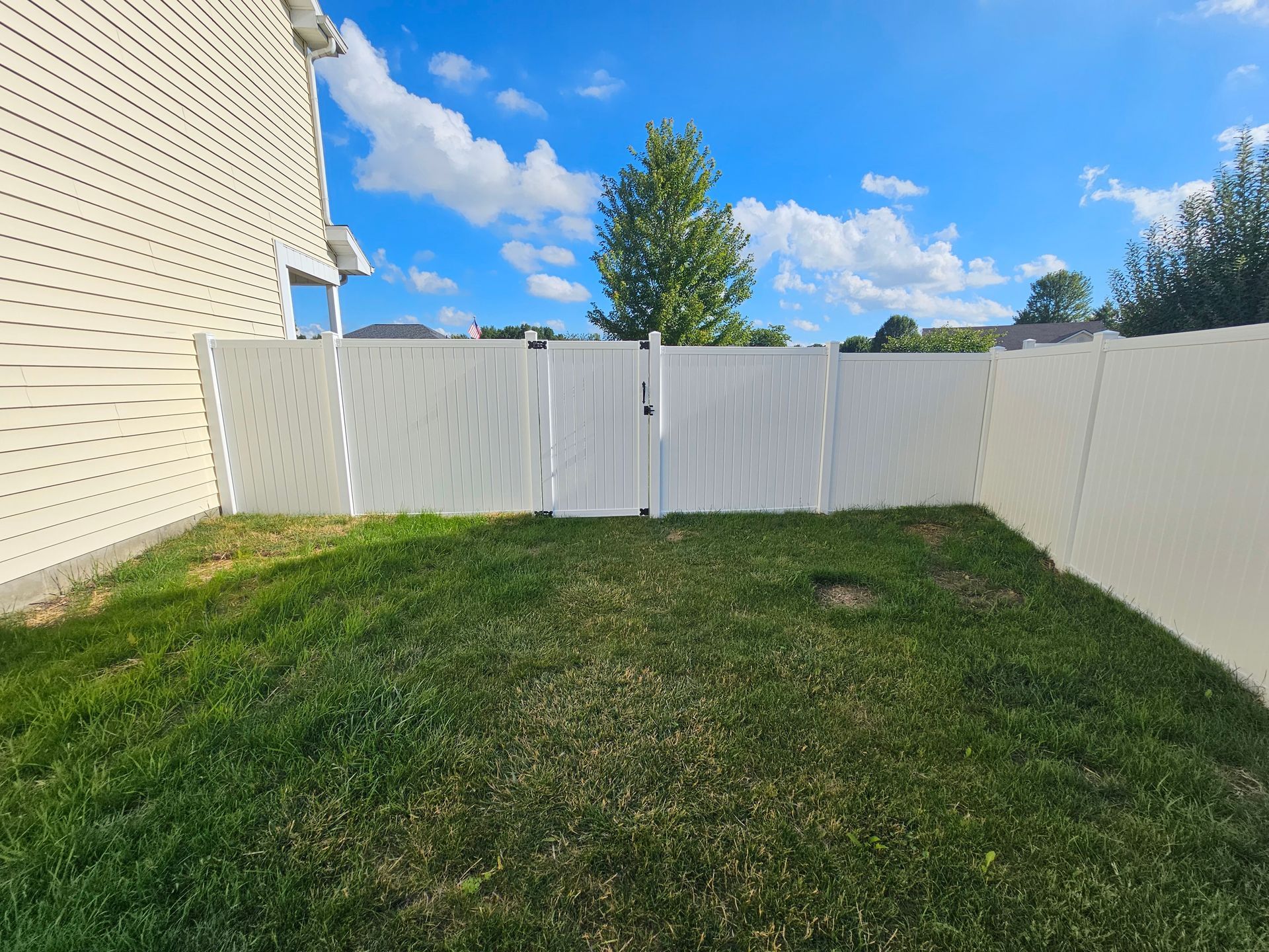 A backyard with a white fence and a gate.