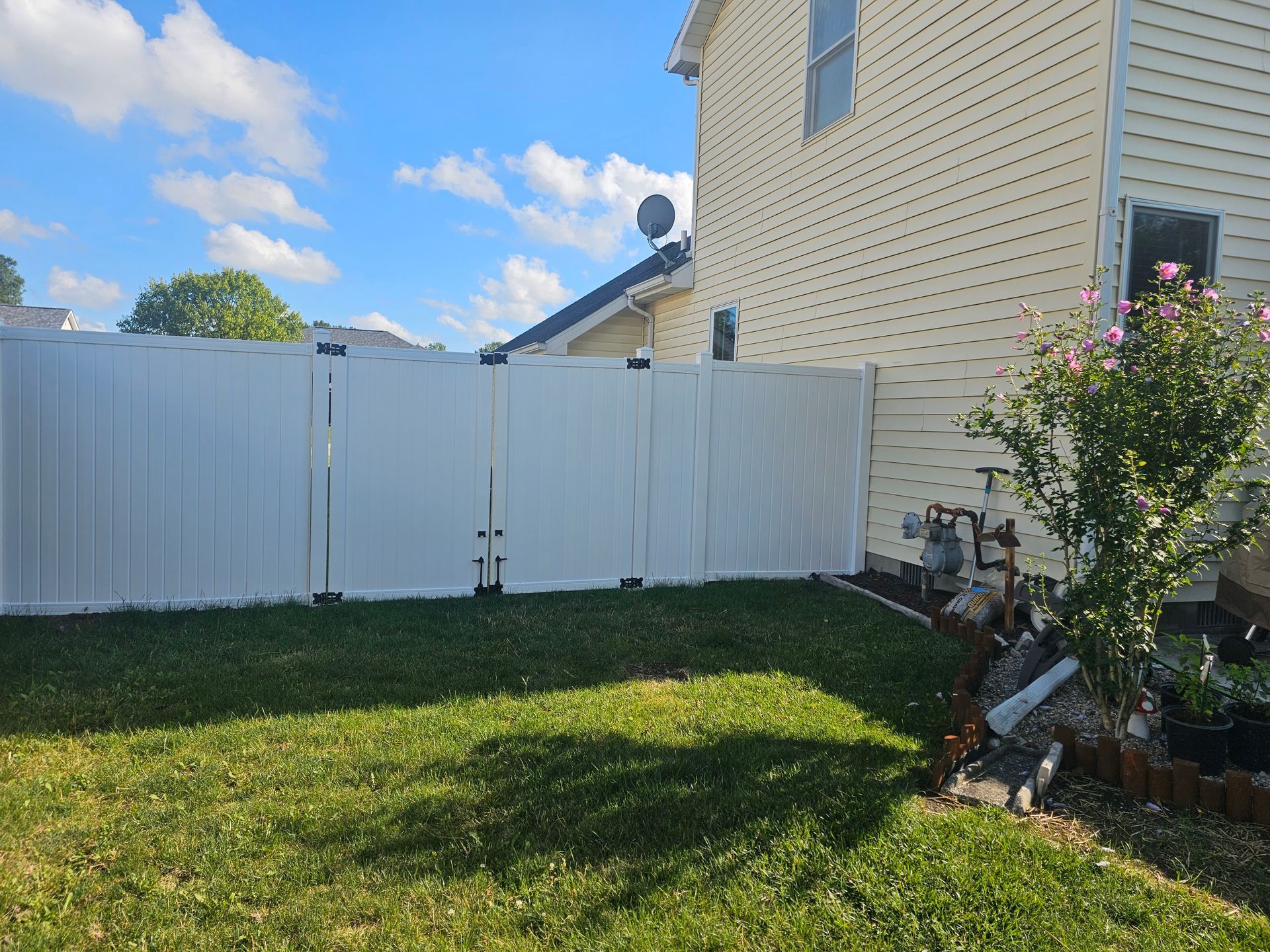 There is a white fence in the backyard of a house.