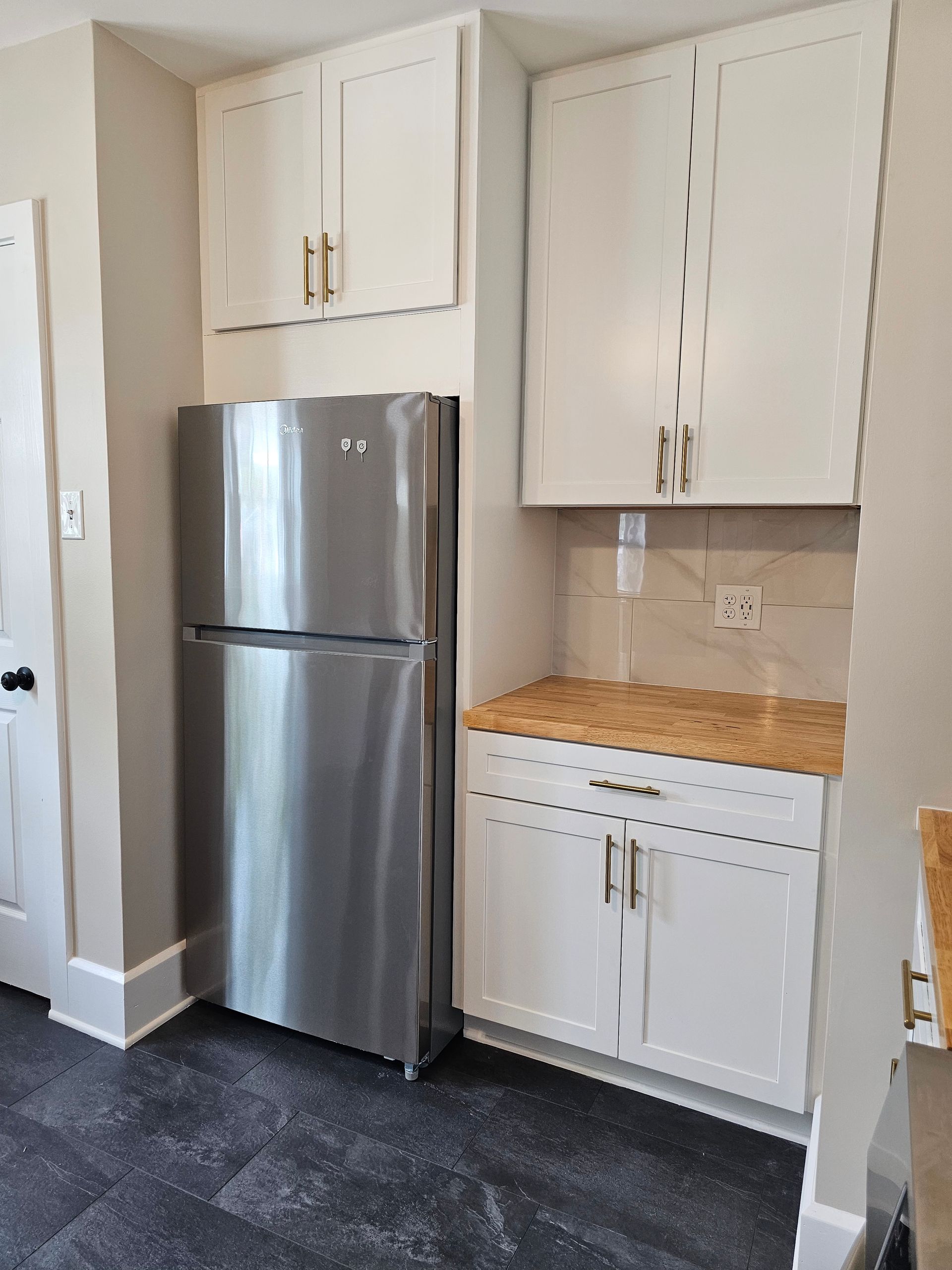 A kitchen with a stainless steel refrigerator and white cabinets