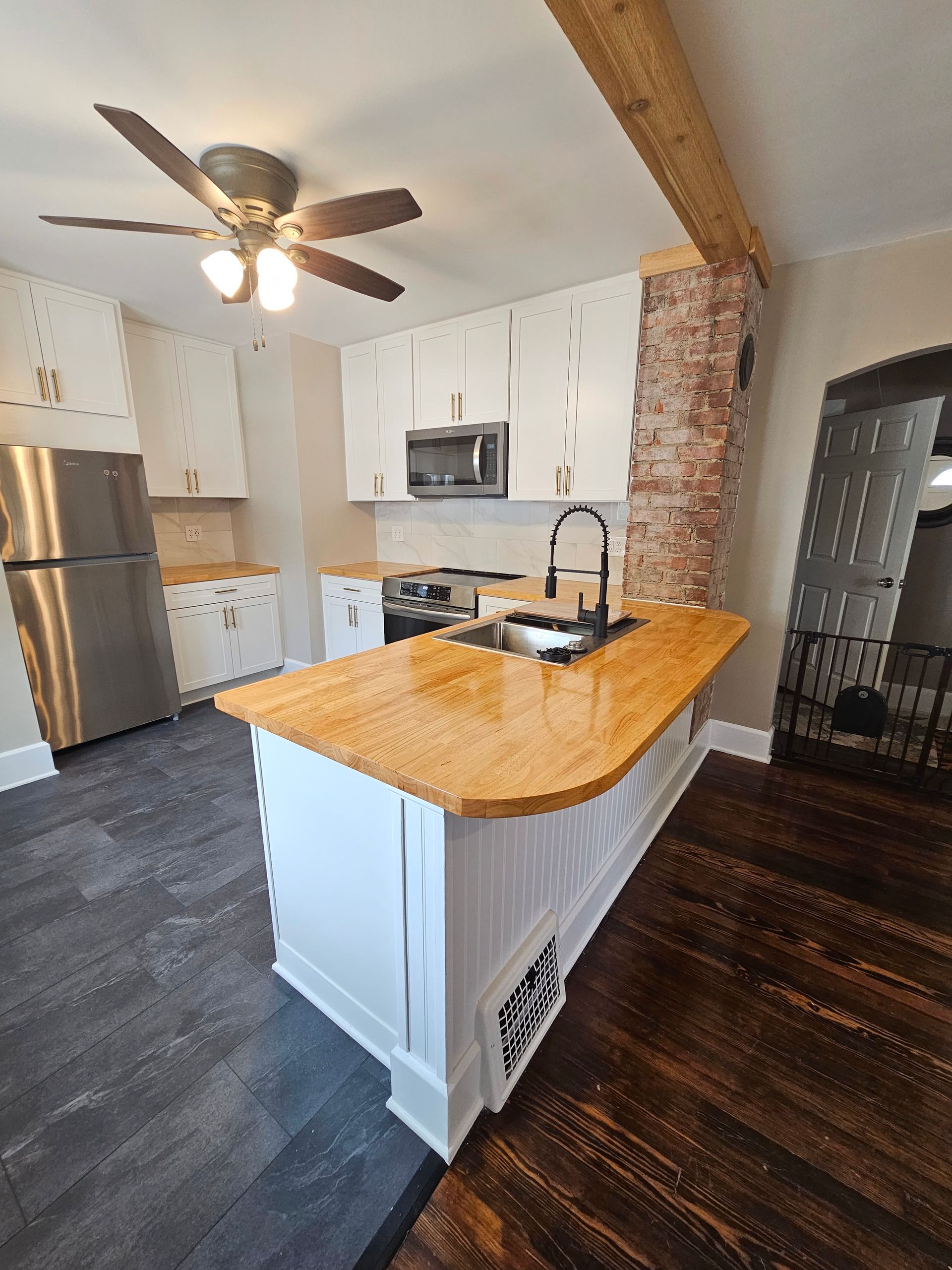 A kitchen with a large island and a ceiling fan.