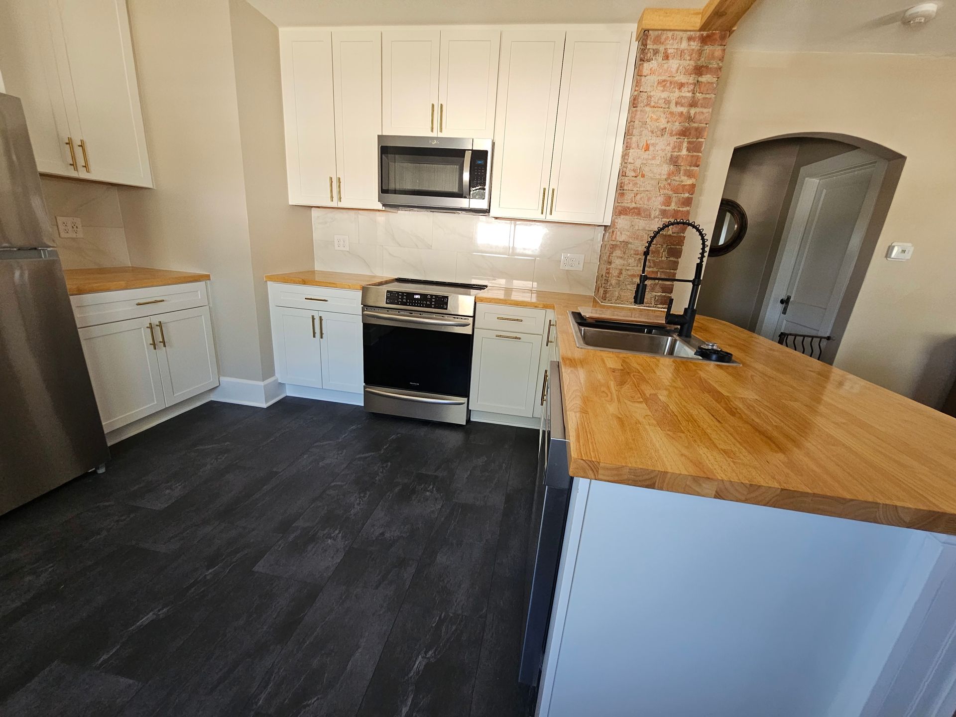 A kitchen with stainless steel appliances and wooden counter tops.