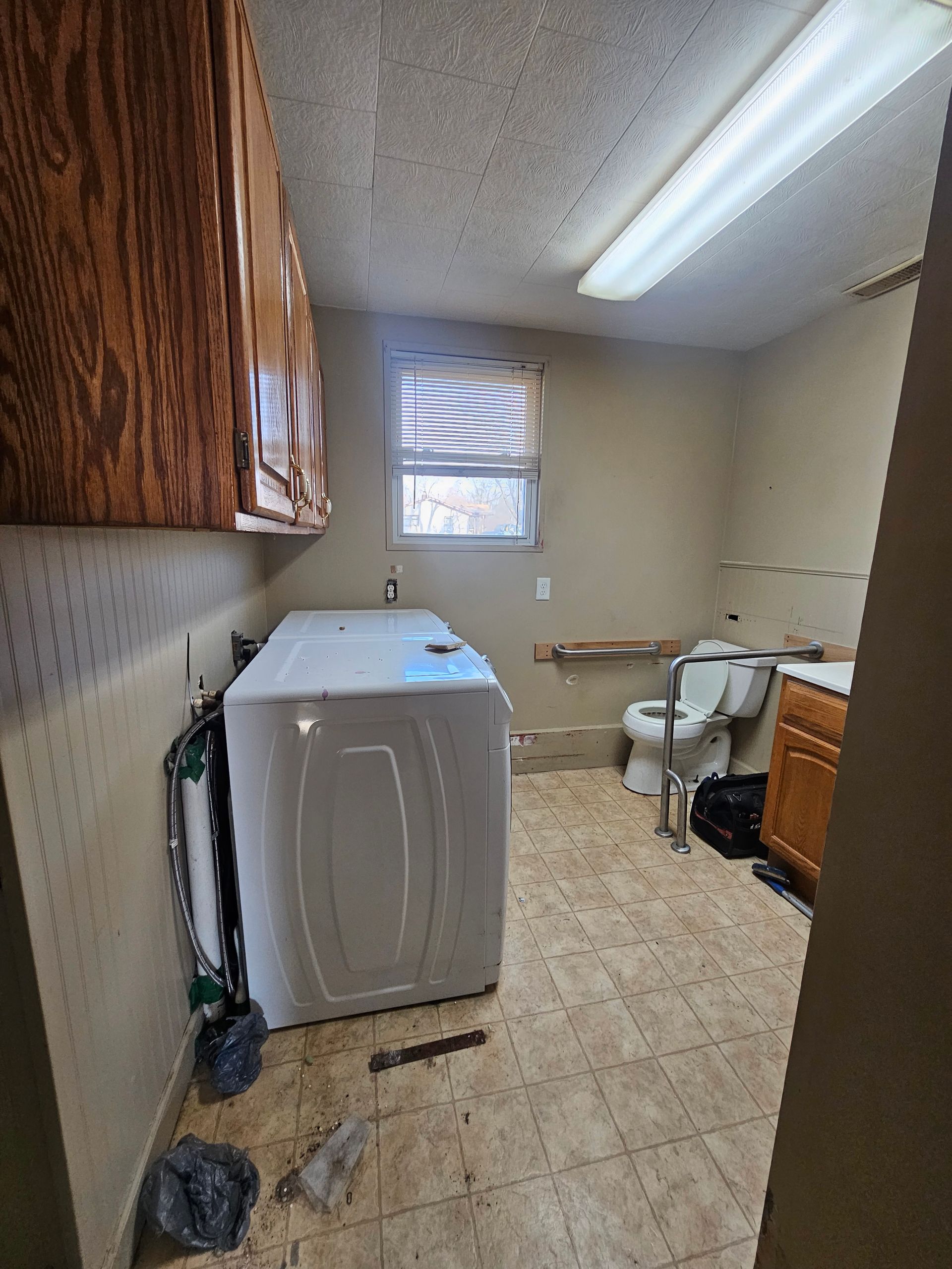 A laundry room with a washer and dryer and a toilet.