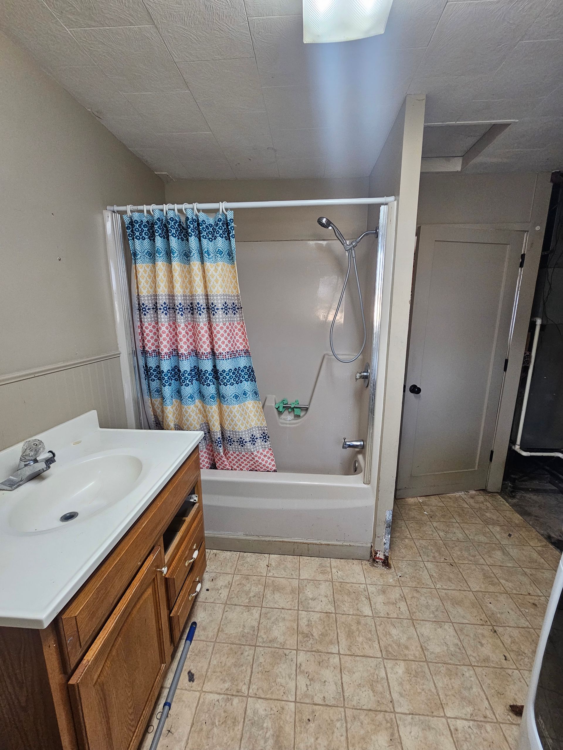 A bathroom with a sink , tub , shower and shower curtain.