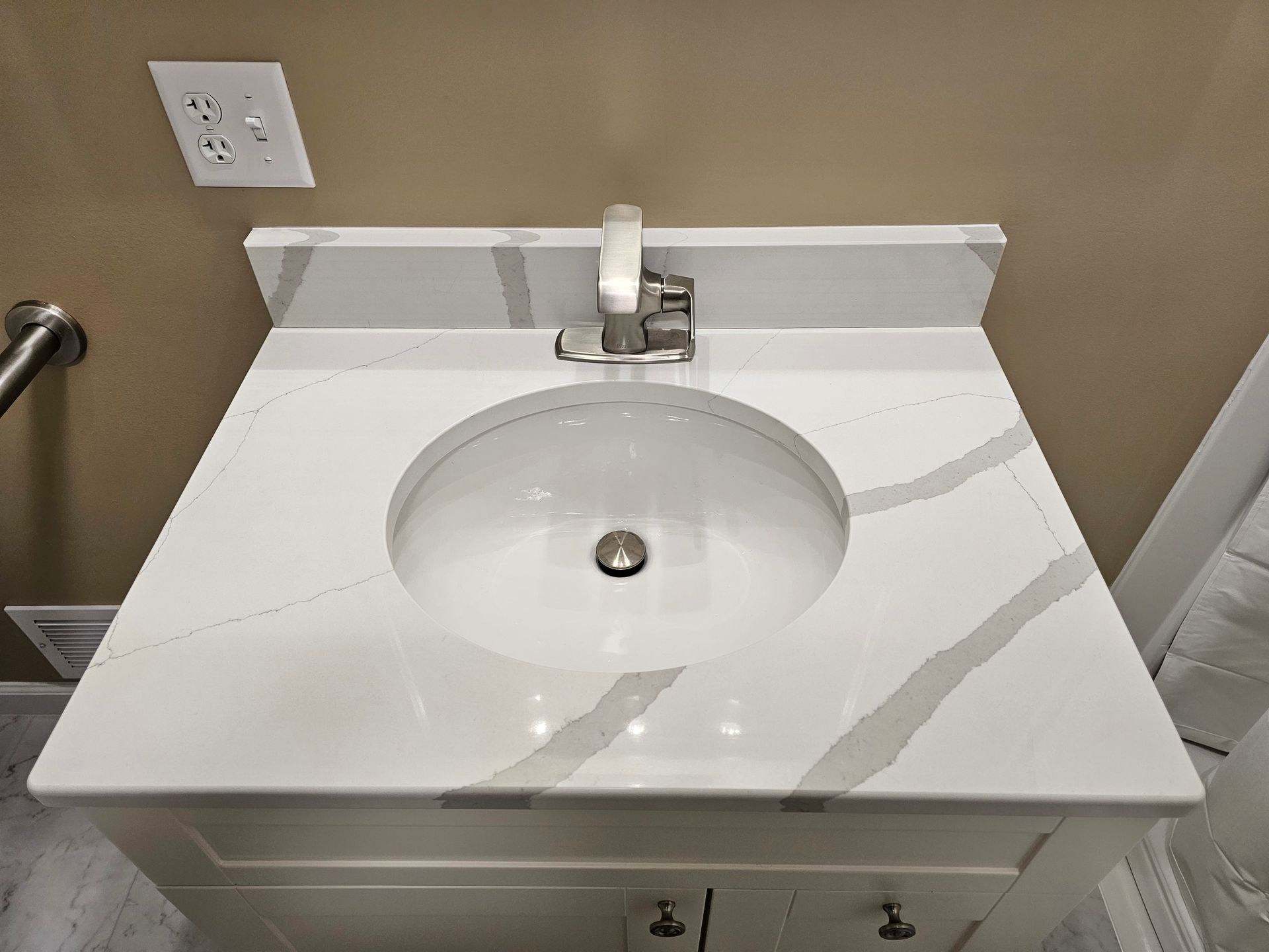 A bathroom sink with a white counter top and a faucet.