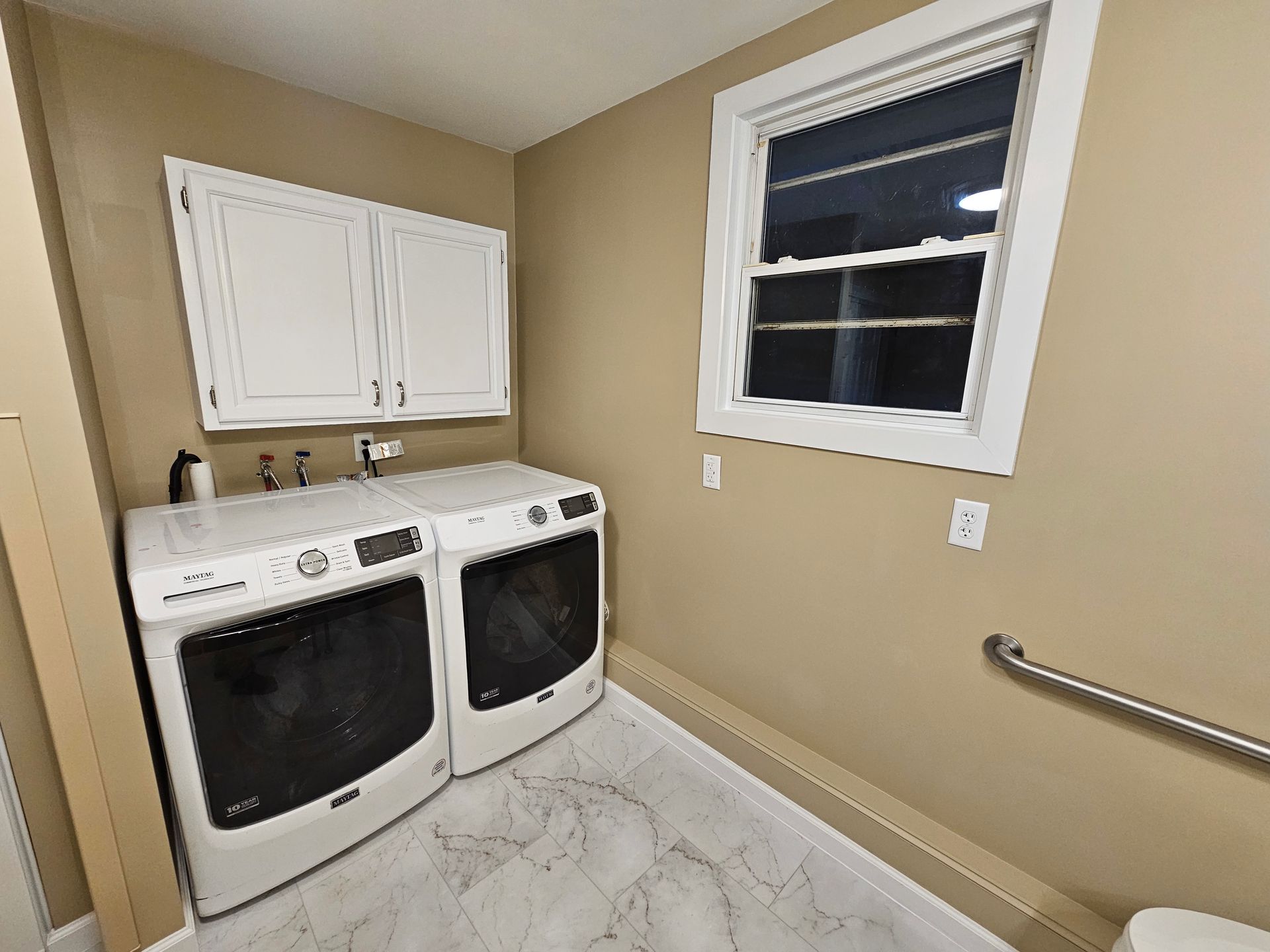 A laundry room with a washer and dryer and a window.