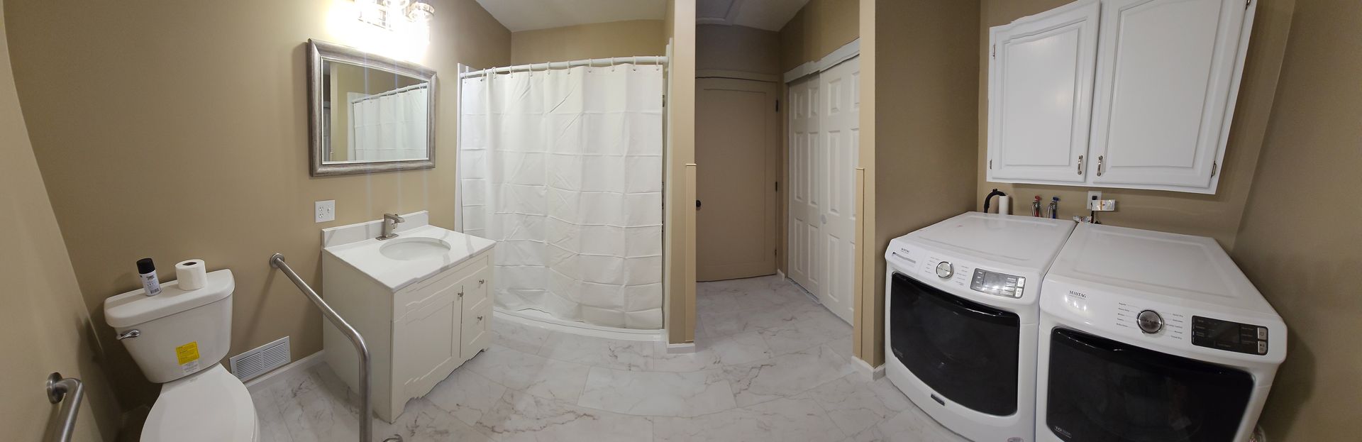 A bathroom with a toilet , sink , washer and dryer.
