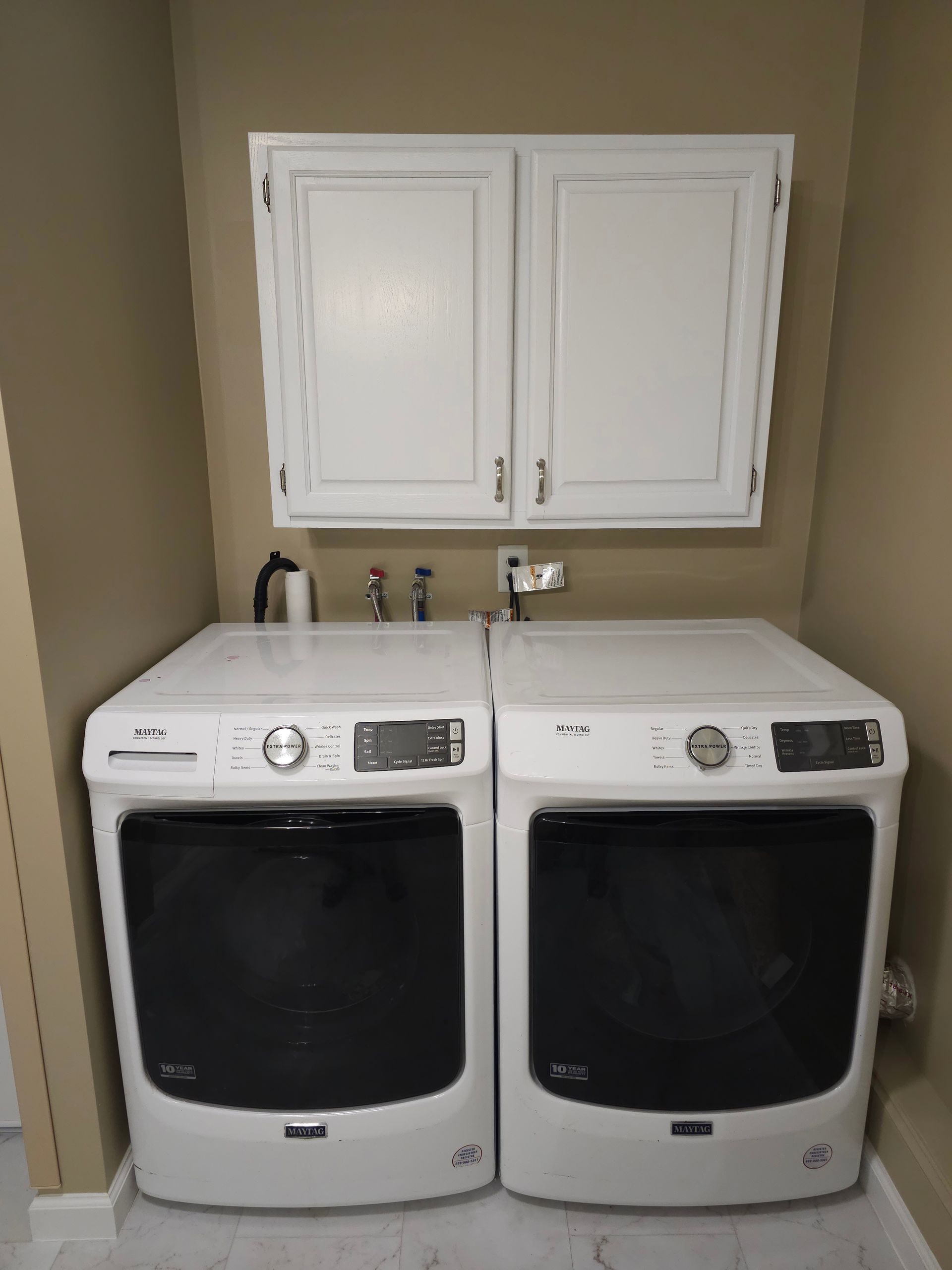 Two white washers and dryers are sitting next to each other in a laundry room.