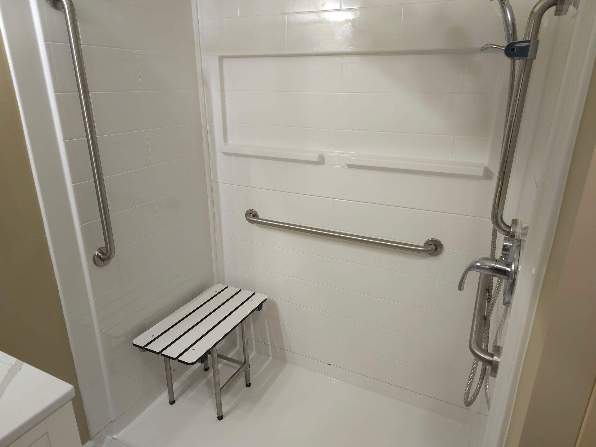 A bathroom with a shower and a stool in it.