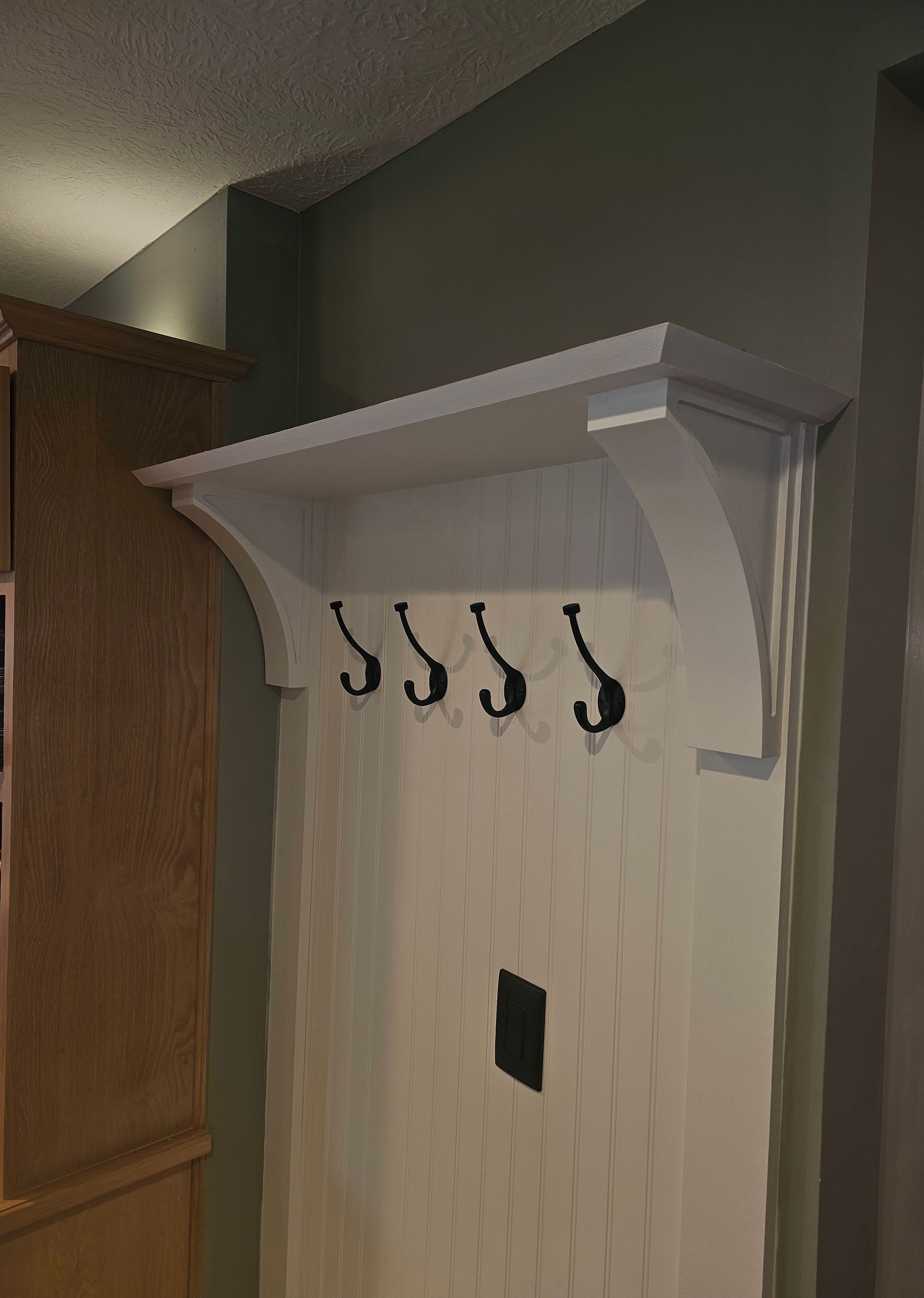 A coat rack with hooks and a shelf above it