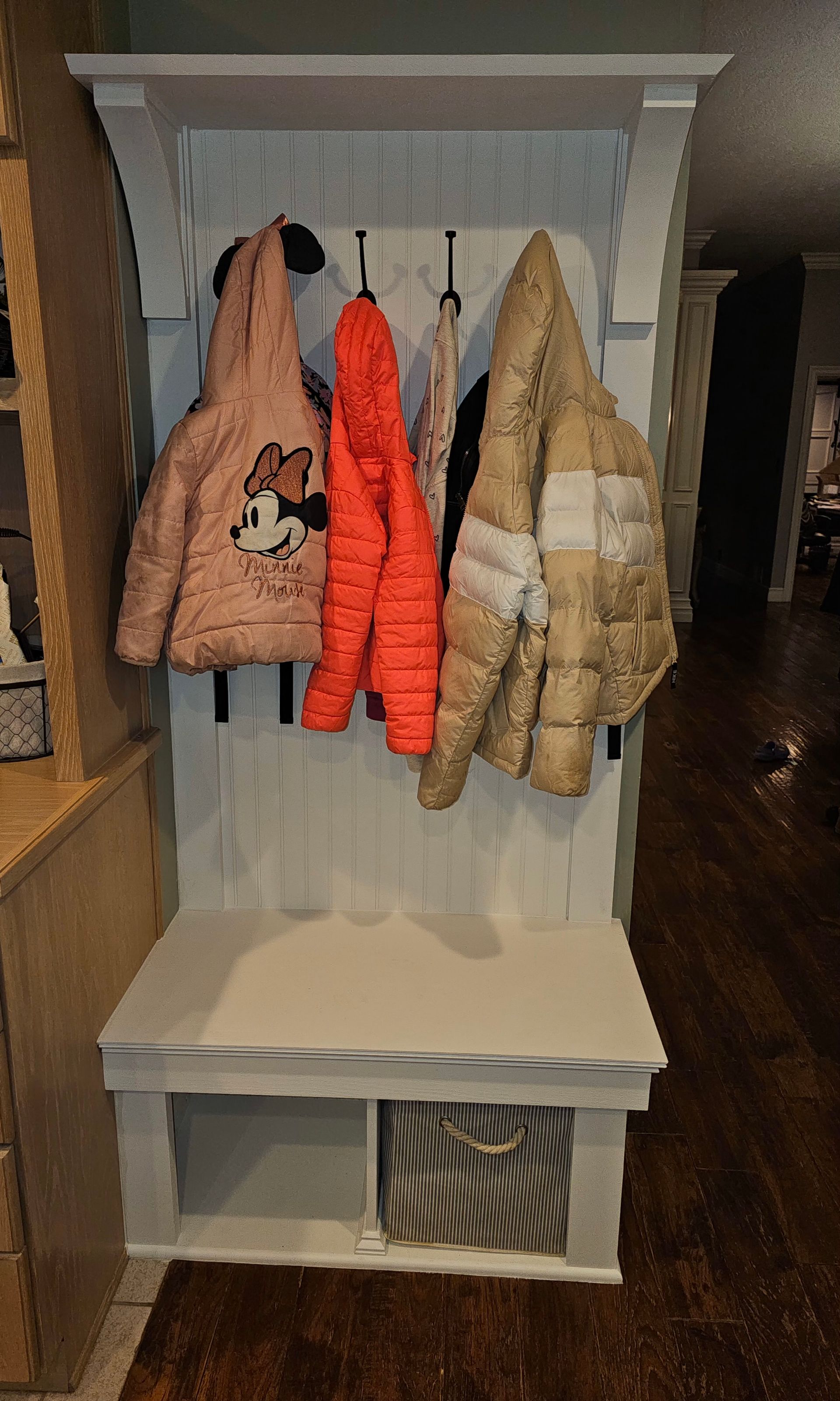 A coat rack with jackets hanging on it in a hallway.