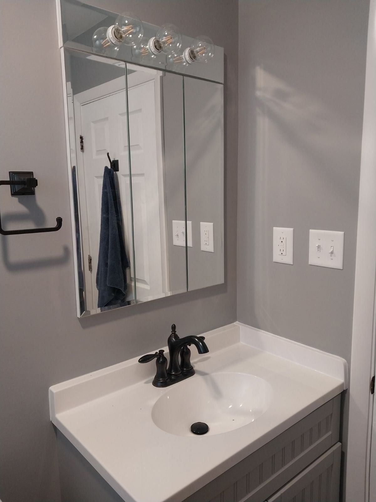 A bathroom with a sink , mirror and towel rack.