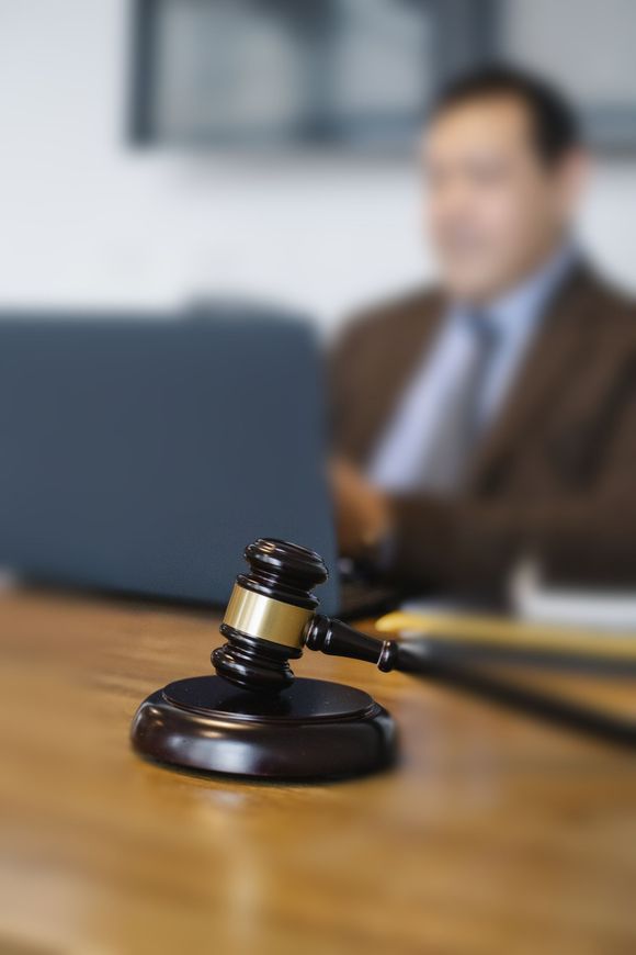 a judge 's gavel is sitting on a wooden table with a man in the background .