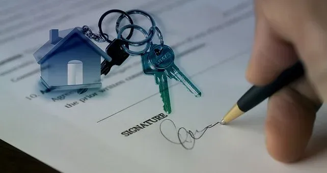 writing signature with key beside and house