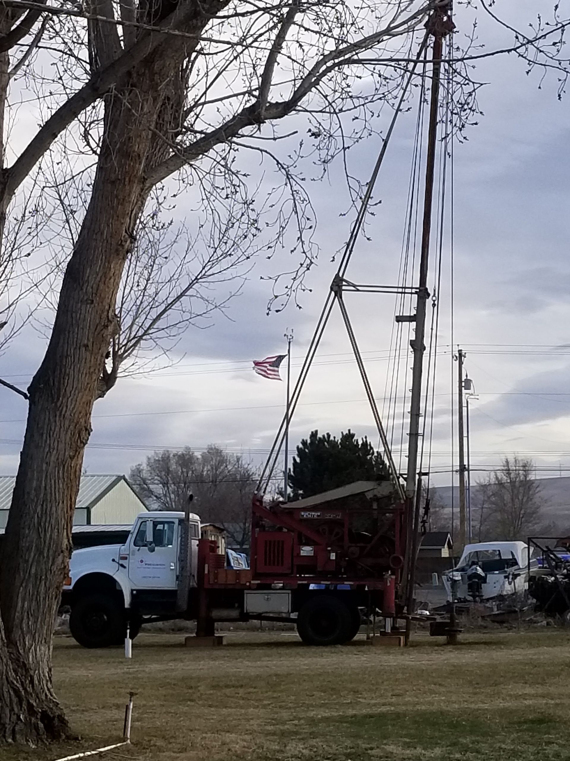 A truck is parked in a grassy field with an american flag in the background