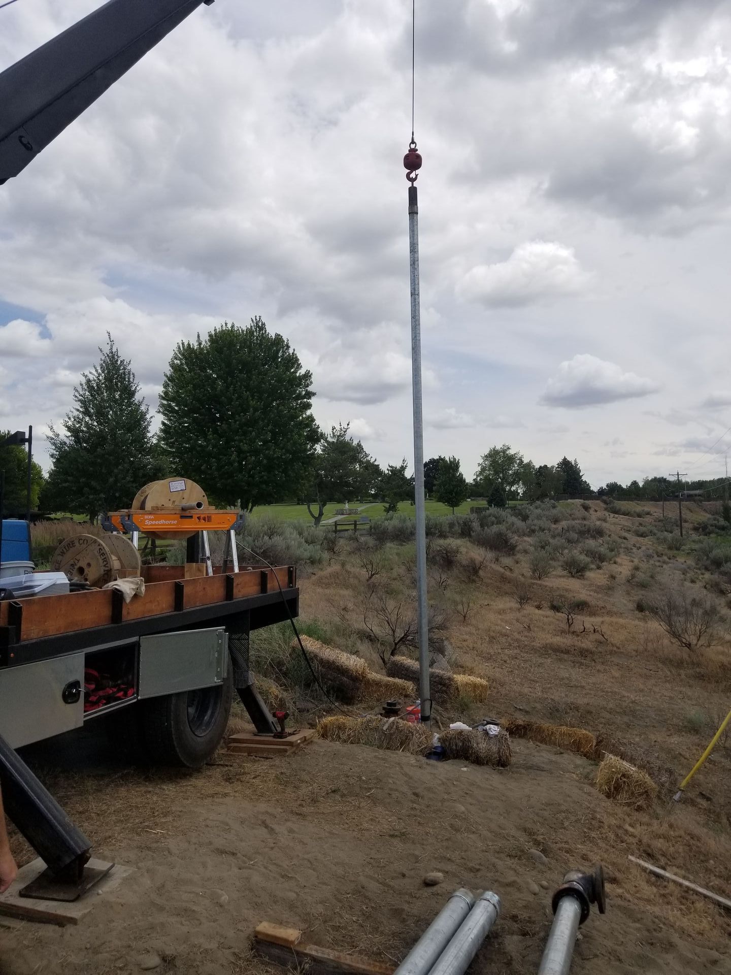 A trailer is sitting in the dirt next to a pole.