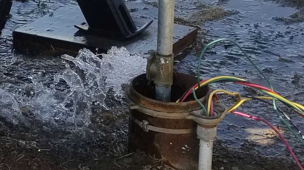 A pipe is being drilled into the ground and water is coming out of it.