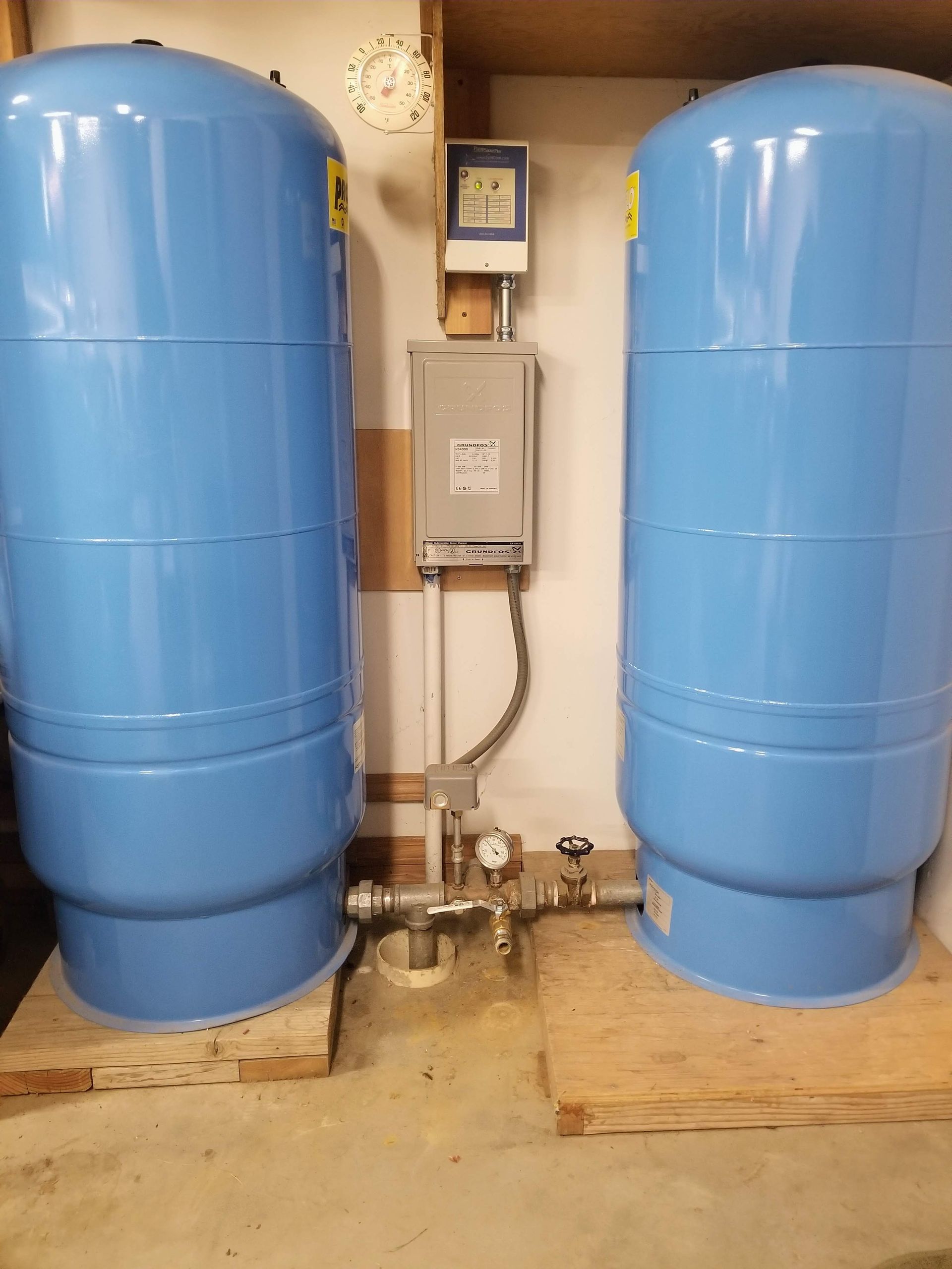 Two blue water tanks are sitting next to each other in a room.