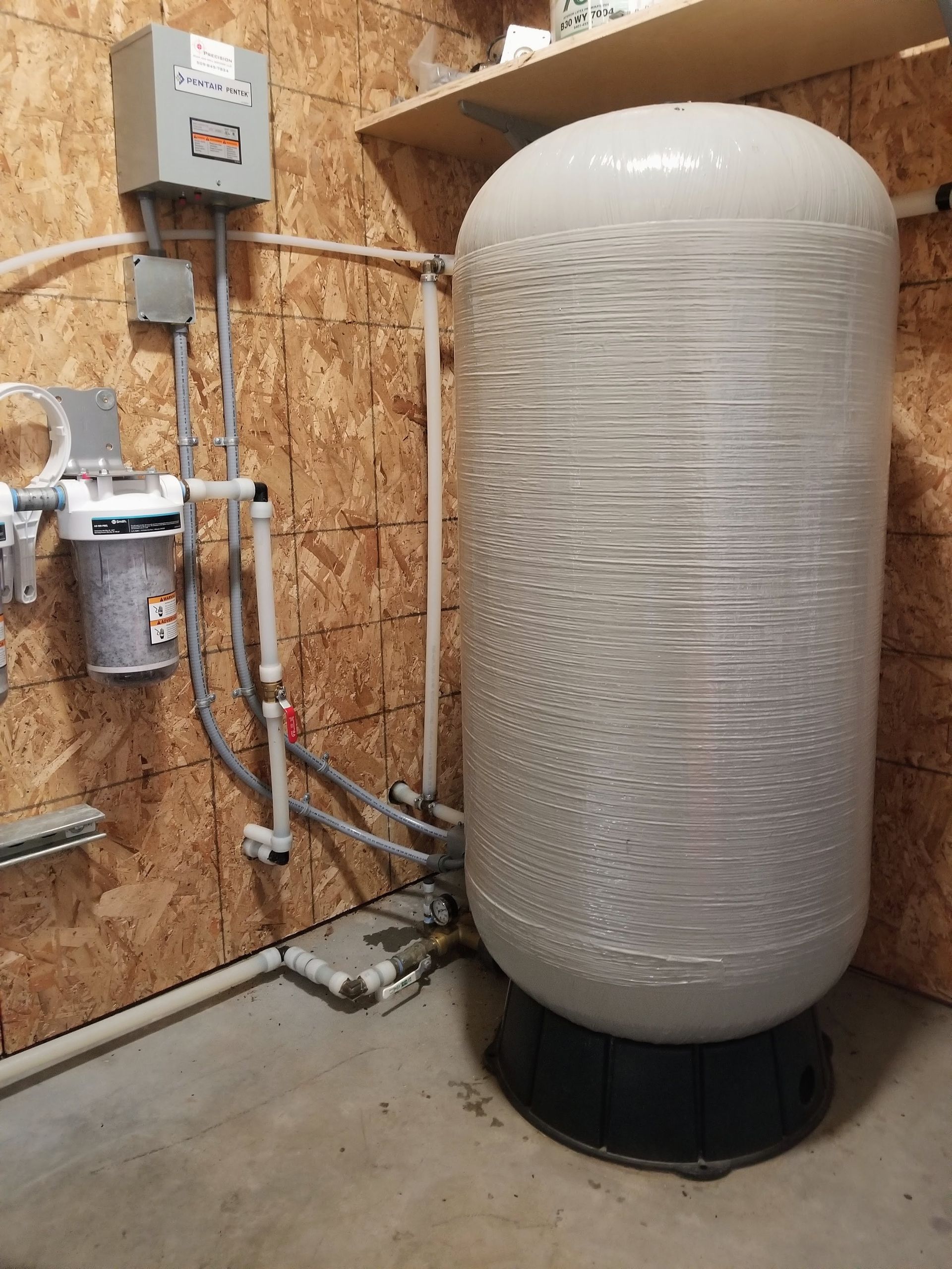 A large white tank is sitting in a room next to a wall.