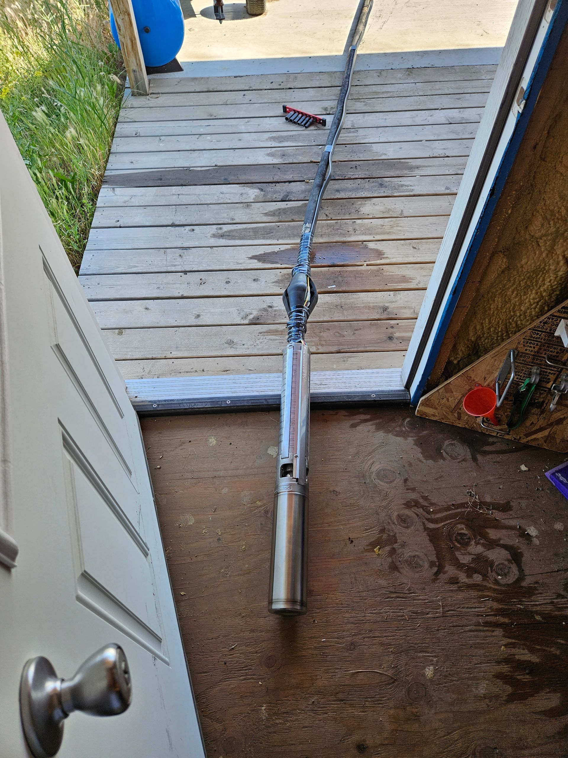 A fishing rod is sitting on the floor next to a door.