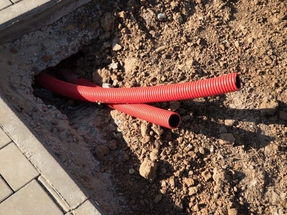 Red Corrugated Conduits Emerging From a Hole in the Ground — Atherton Location Services In Atherton, QLD