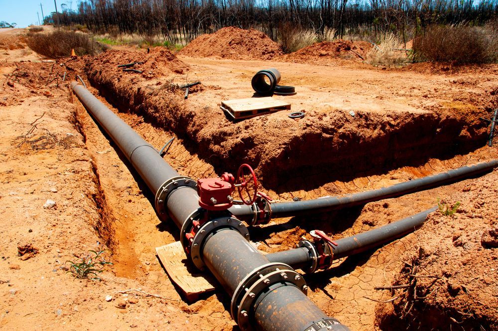 Large Metal Pipes in a Trench, Red Valve, in a Construction — Atherton Location Services In Atherton, QLD