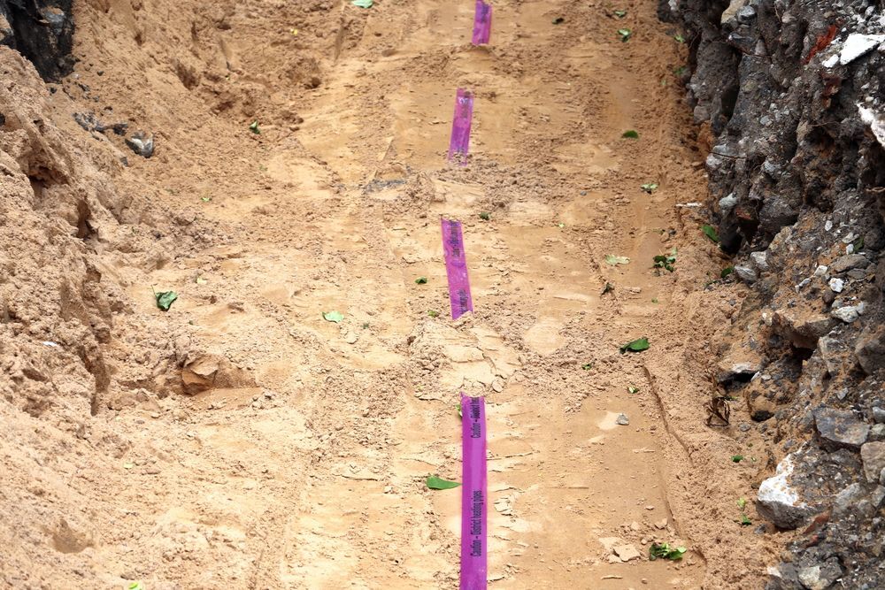 A Dug Trench With a Purple Measuring Stick — Atherton Location Services In Atherton, QLD