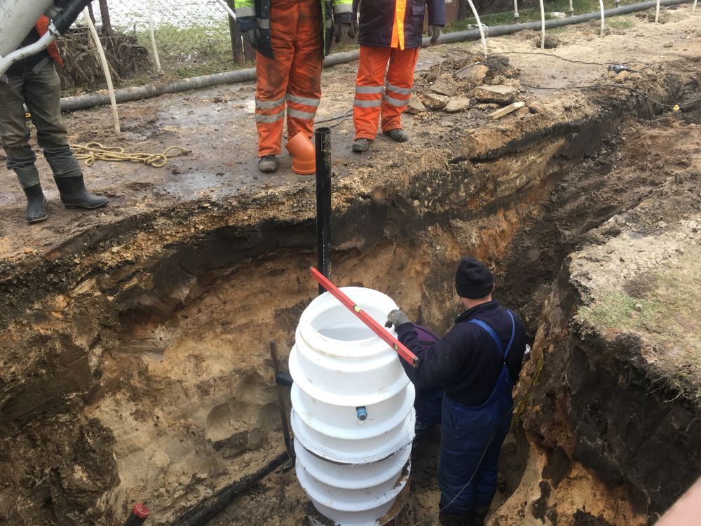 Construction Workers Install a White Septic Tank in a Trench — Atherton Location Services In Mareeba, QLD