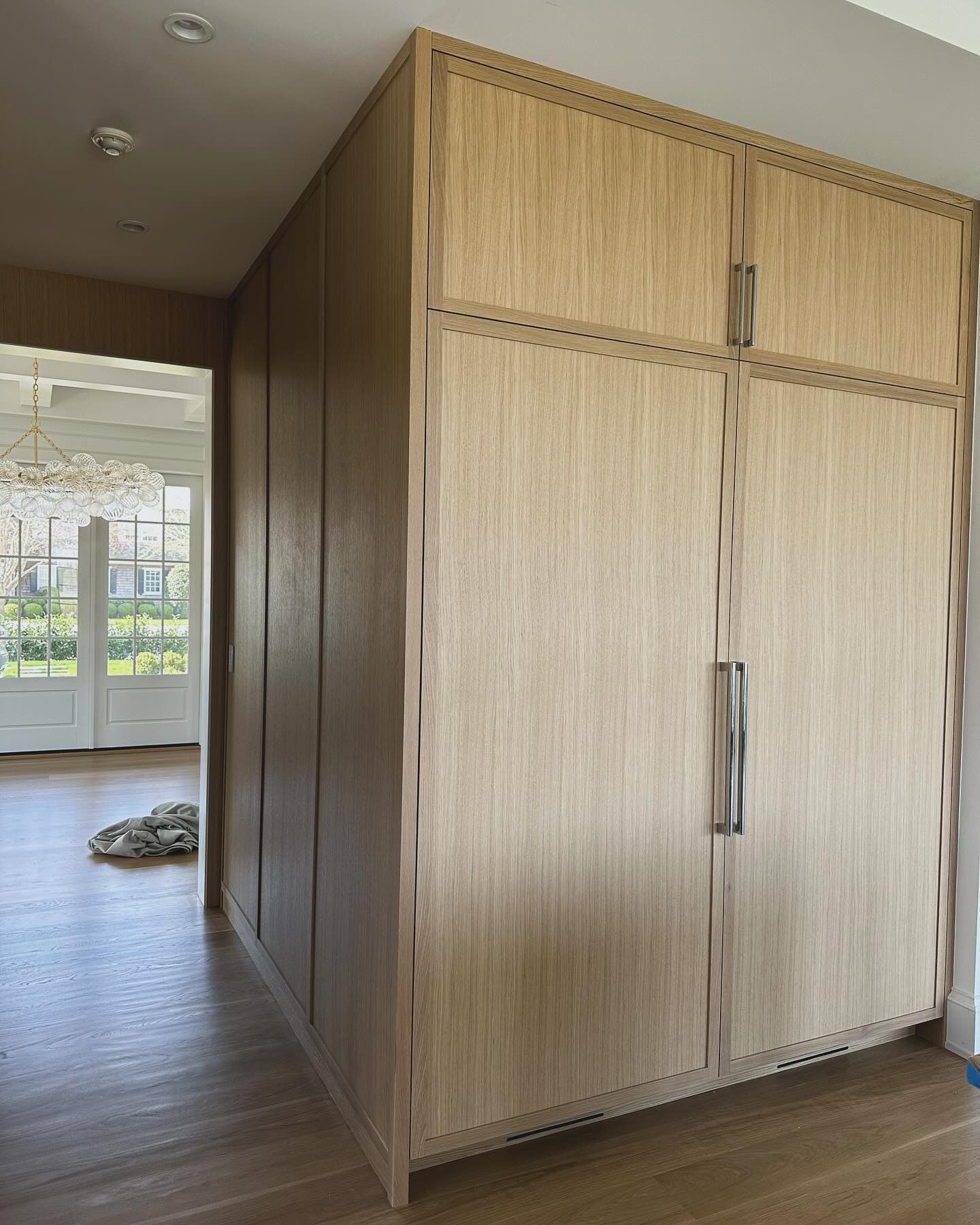 Wooden closet in a hallway; light wood panels and brushed metal handles.
