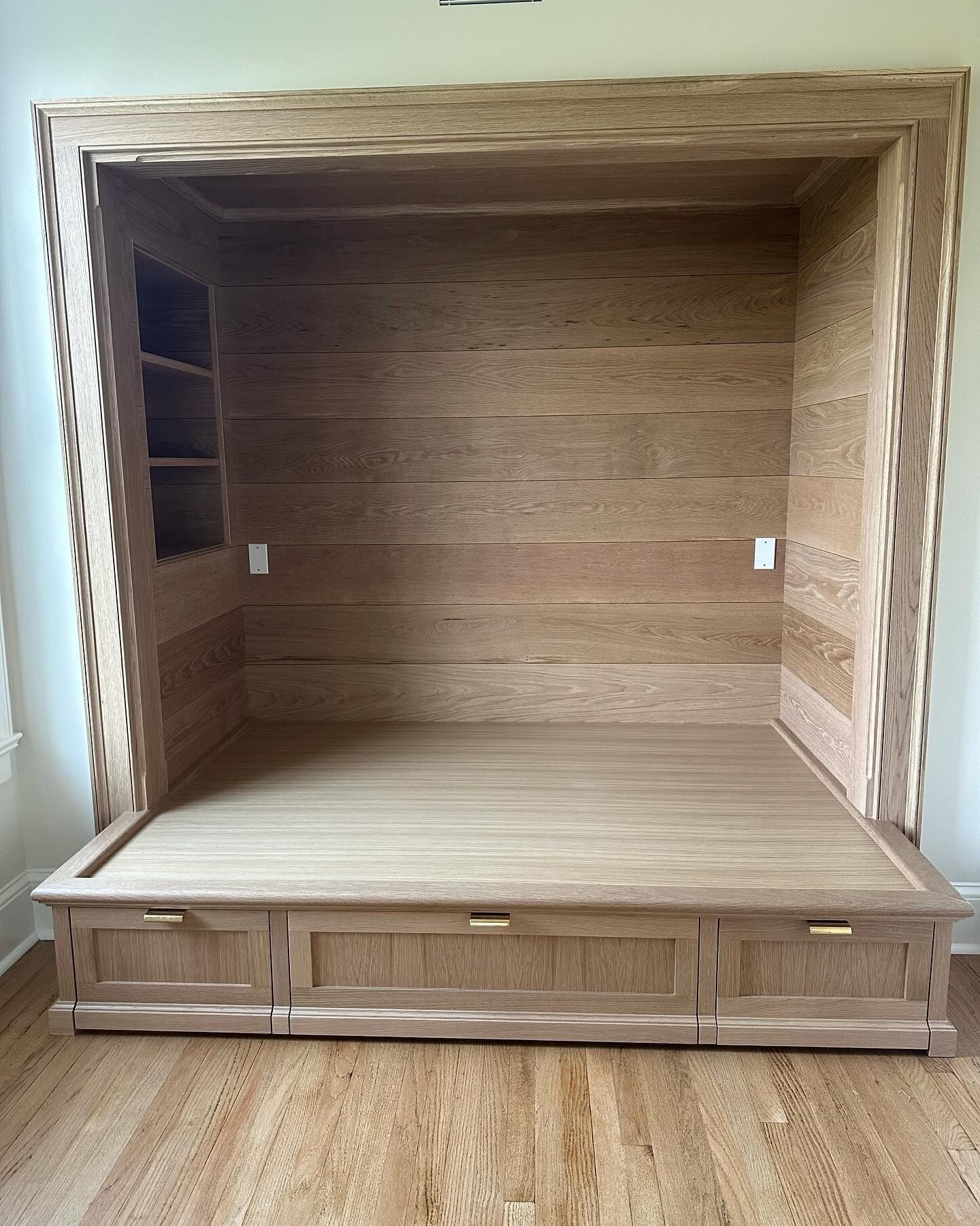 Built-in wooden bed frame with drawers, side shelves, and overhead lighting fixtures.