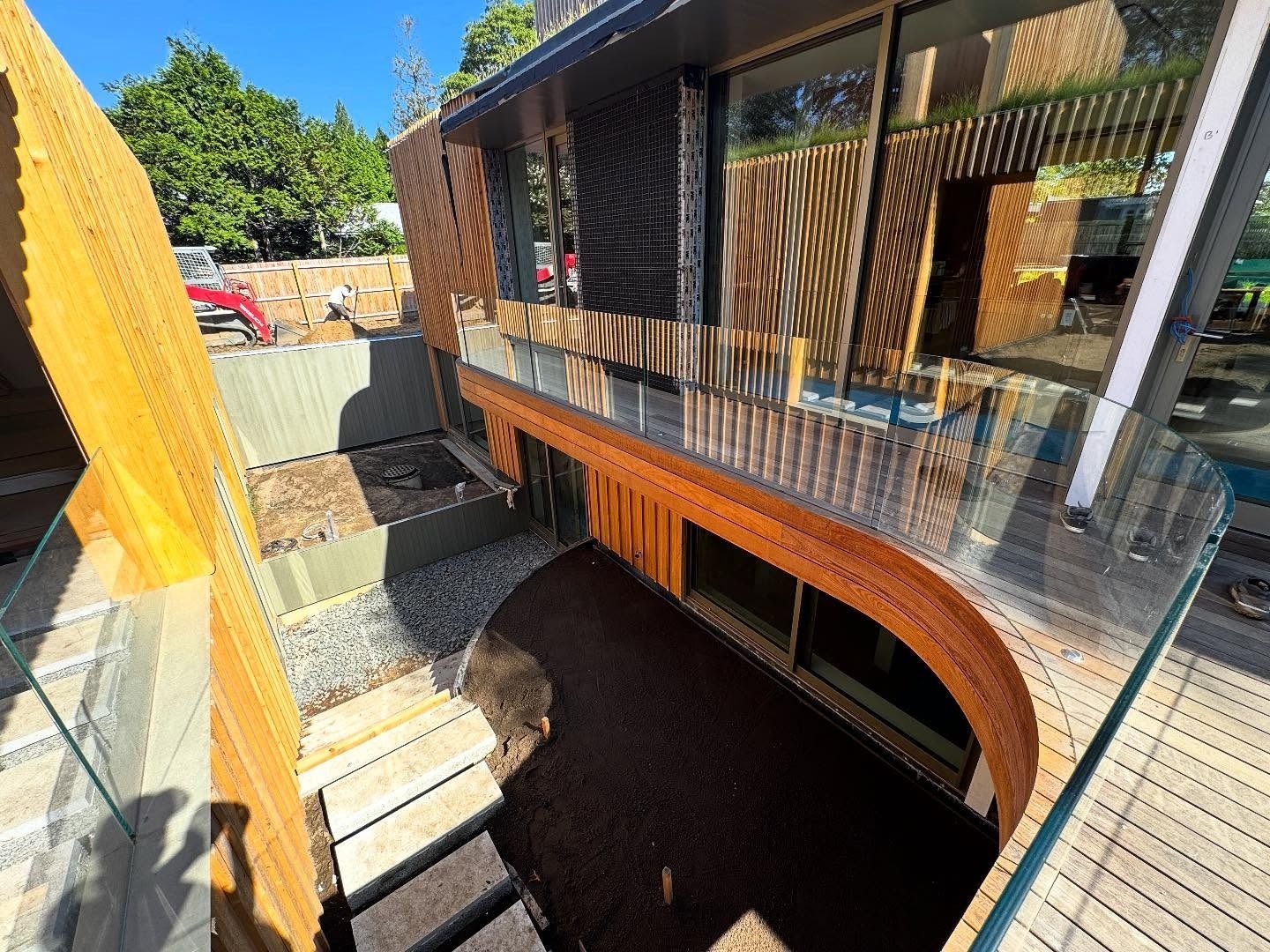 Modern building exterior with wooden and glass facade. Terraced entrance with steps.