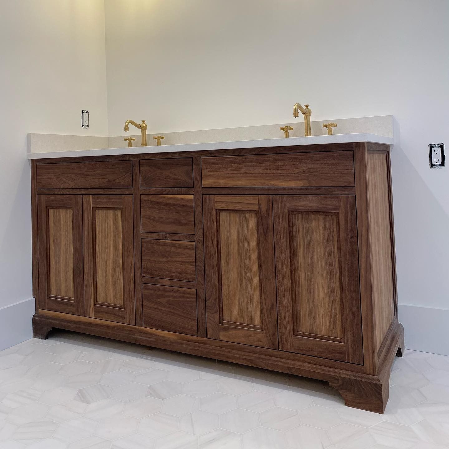 Wooden bathroom vanity with white countertop and gold fixtures.
