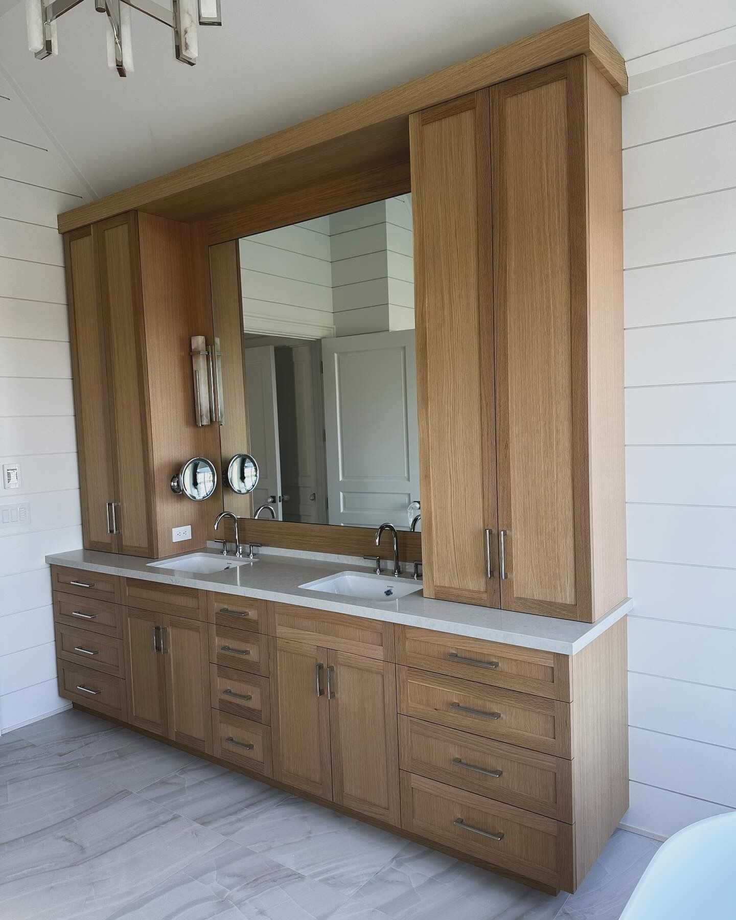 Light oak bathroom vanity with storage cabinets, drawers, double sinks, and a large mirror.