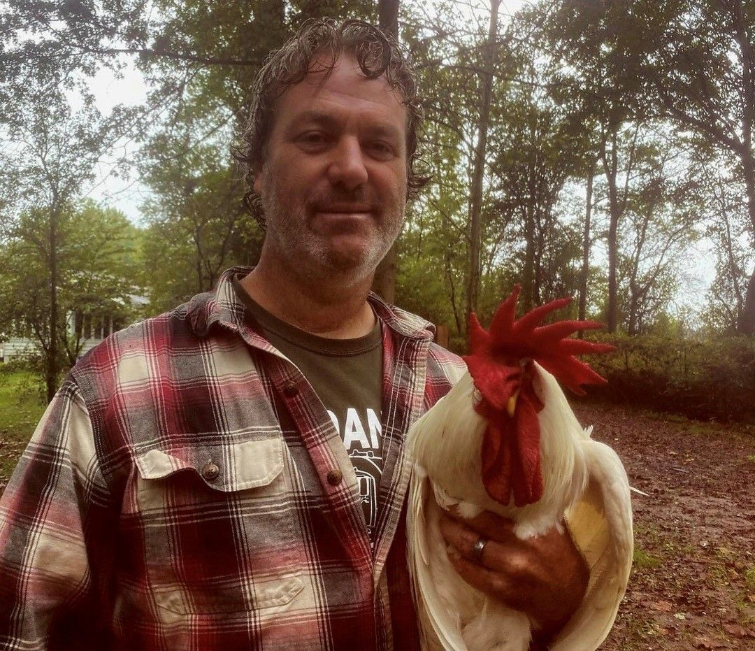A septic tank truck is driving down a street in front of a house.