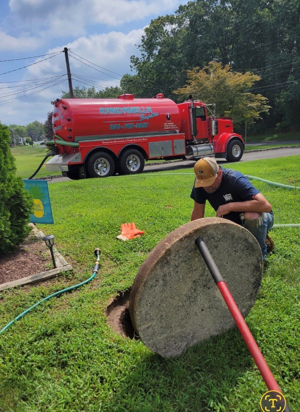 A man is kneeling down to open a manhole cover.