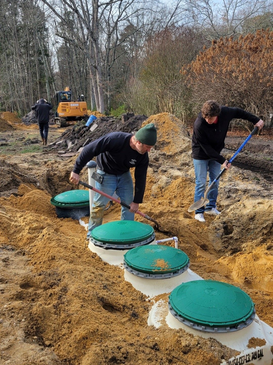 A concrete septic tank is being built in a dirt field.