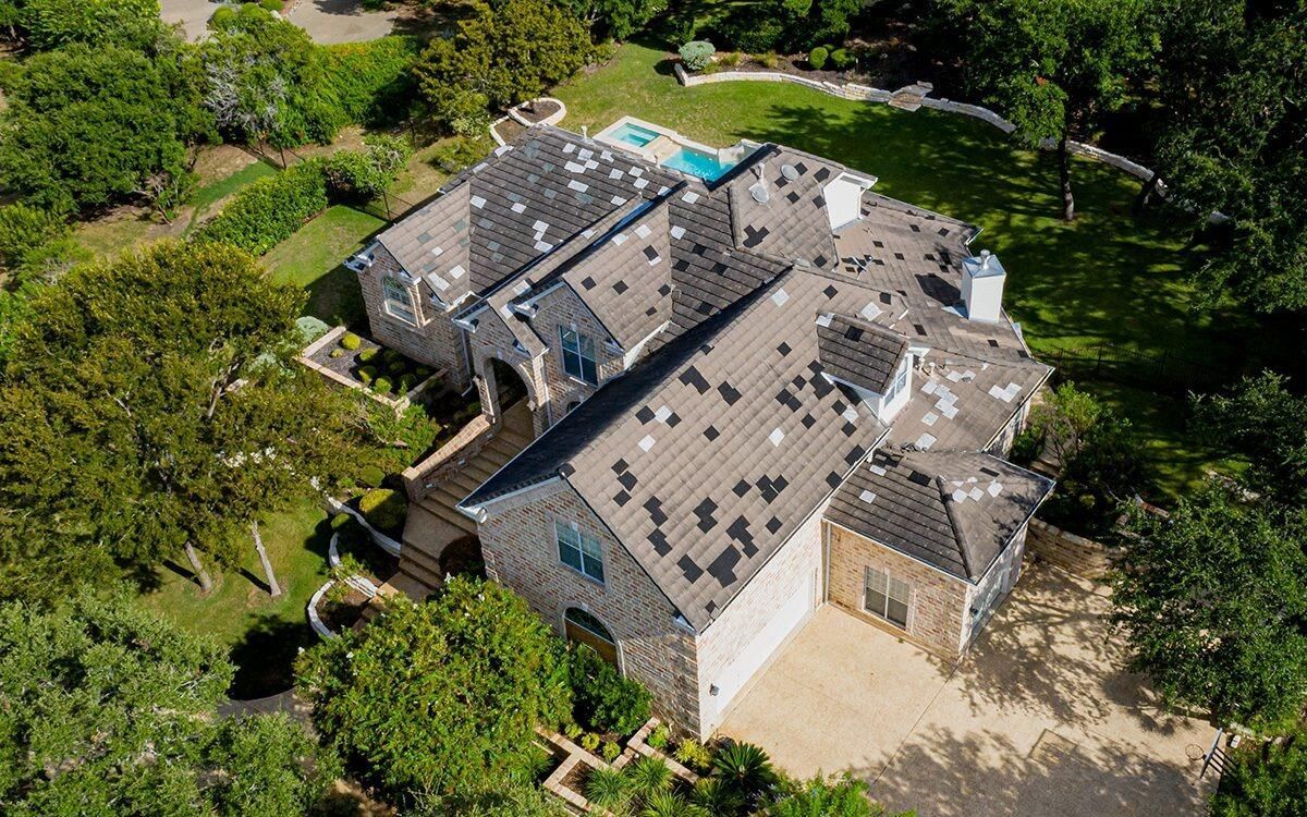 aerial view of a luxury residential home with roof under maintenance/repair