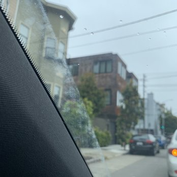 View from a car window: buildings, cars on the street, and utility lines under a cloudy sky.