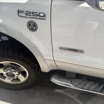 White Ford F-250 truck's front quarter panel with badging, including 