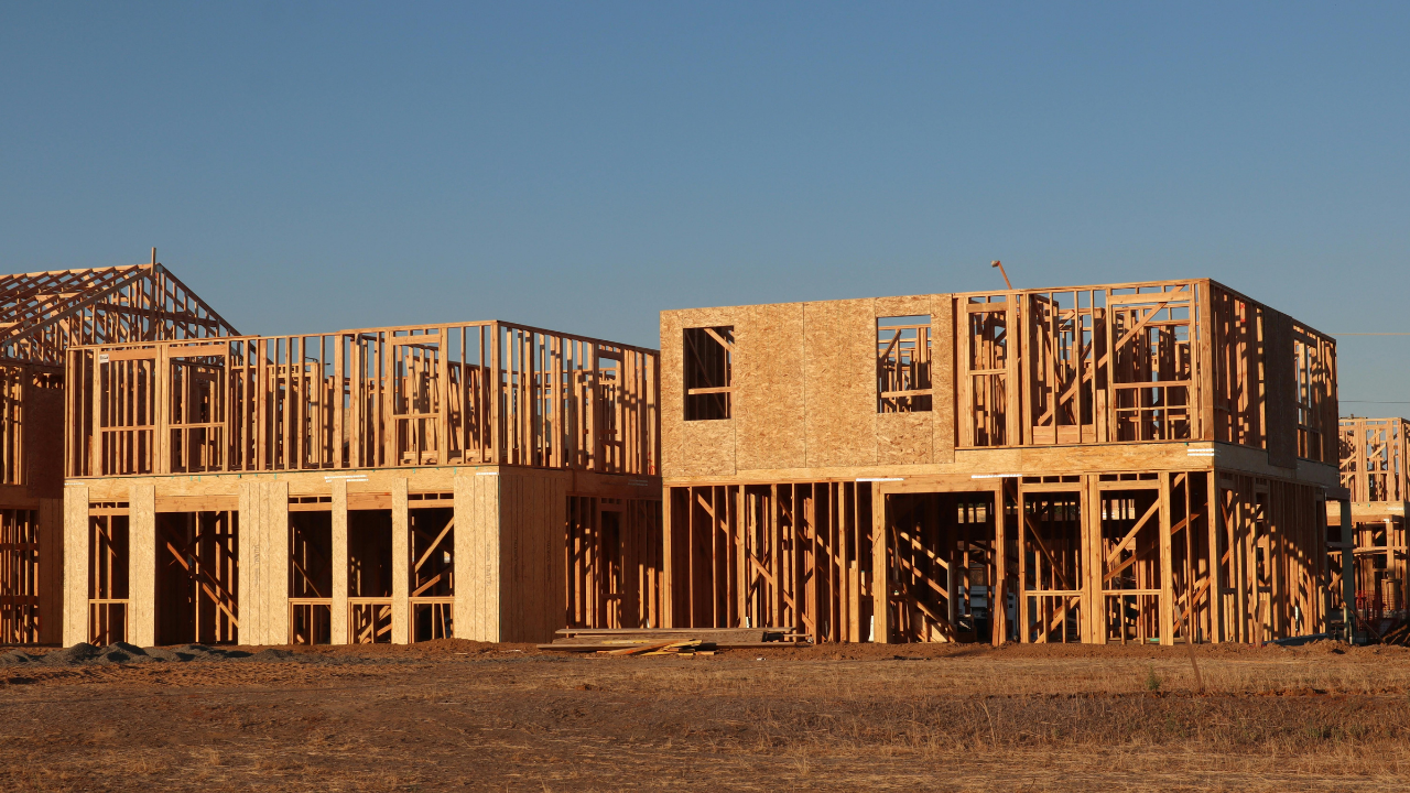 Wooden frames of new houses under construction against a blue sky.