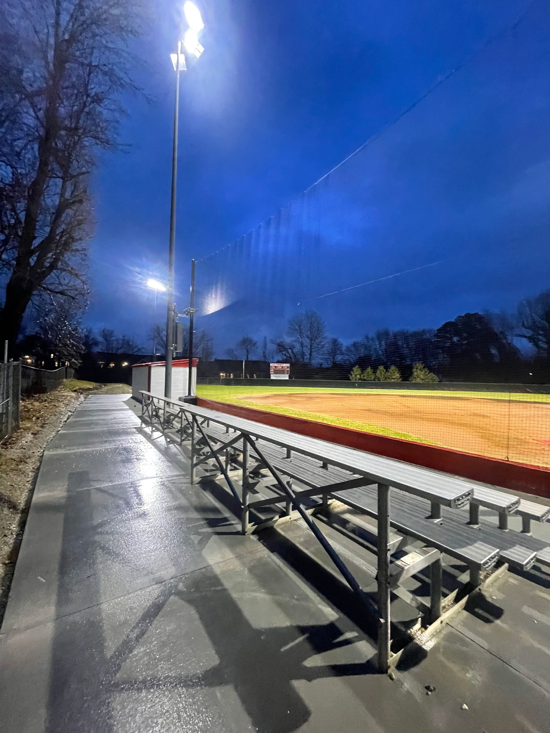 A stadium with bleachers and a field at night.