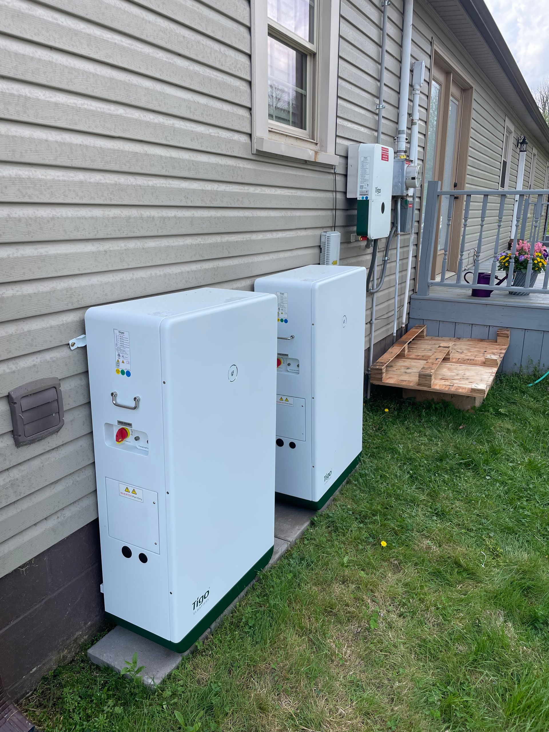 Two white boxes are sitting on the side of a house.