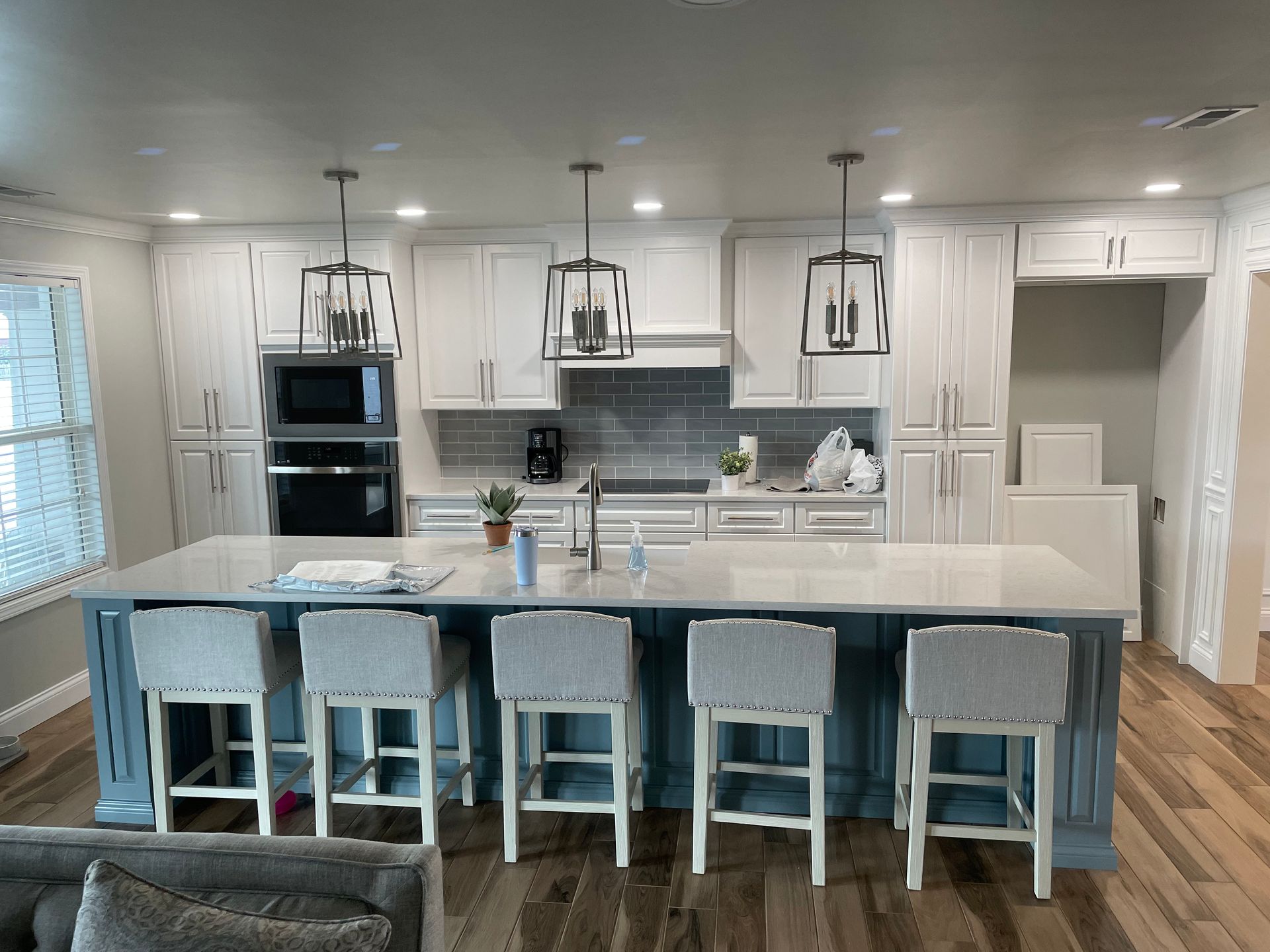 A kitchen with white cabinets and a large island with stools.