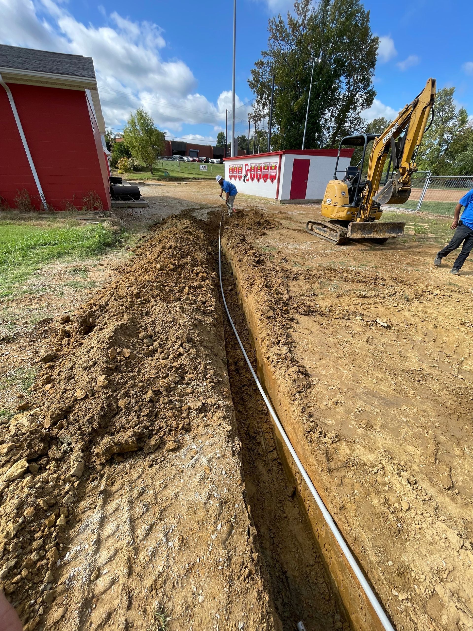 A yellow excavator is digging a trench in the dirt.